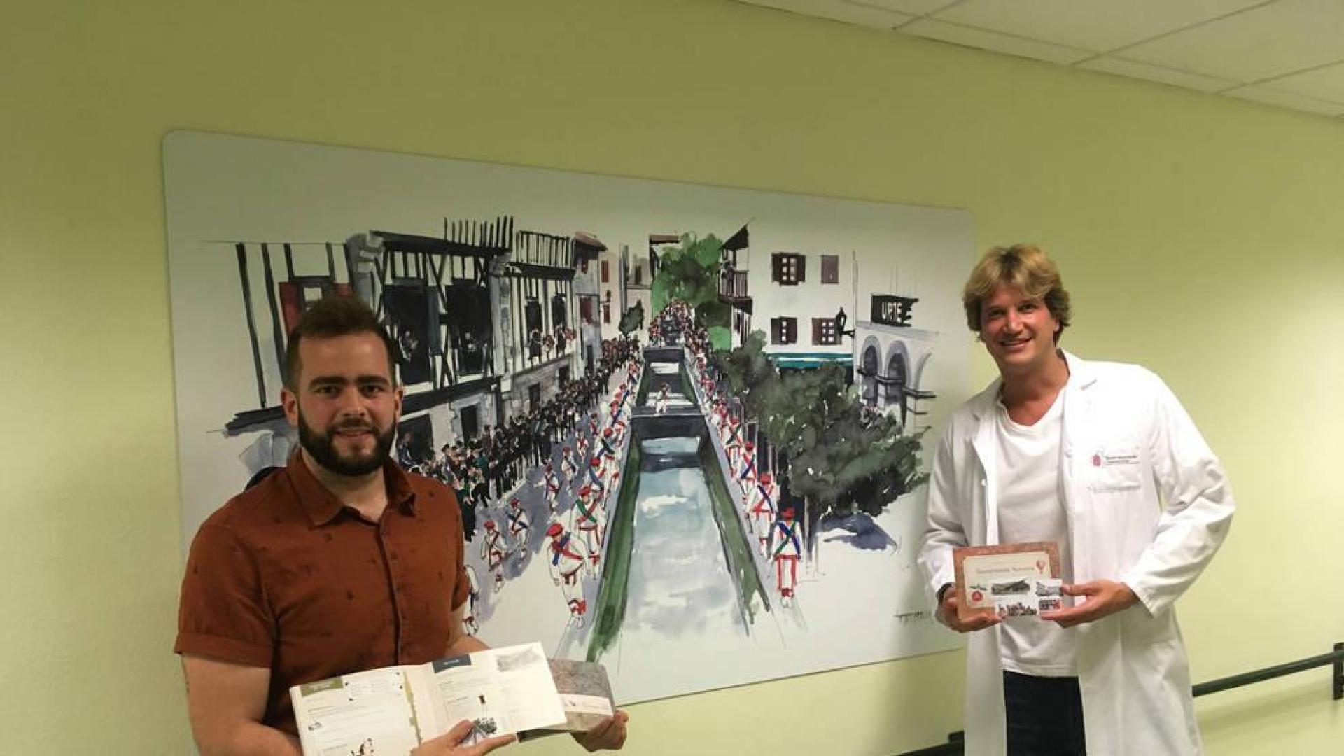 César Cuevas Lara (izda) y Fabricio Zambom Ferraresi con los 'diarios de viaje' delante de una acuarela de Lesaka, en la planta de Geriatría del CHN