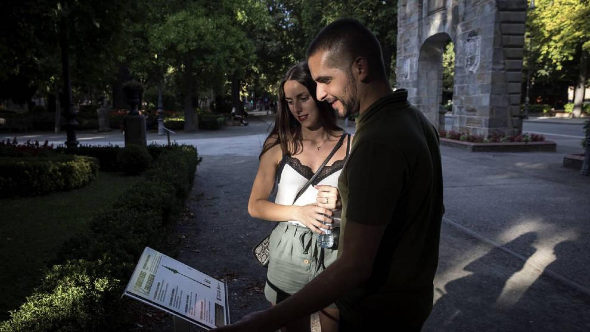 Una pareja observa el panel de la Taconera que señala la secuoya del parque y su relación con la reina americana Braulia de la Comparsa de Gigantes.