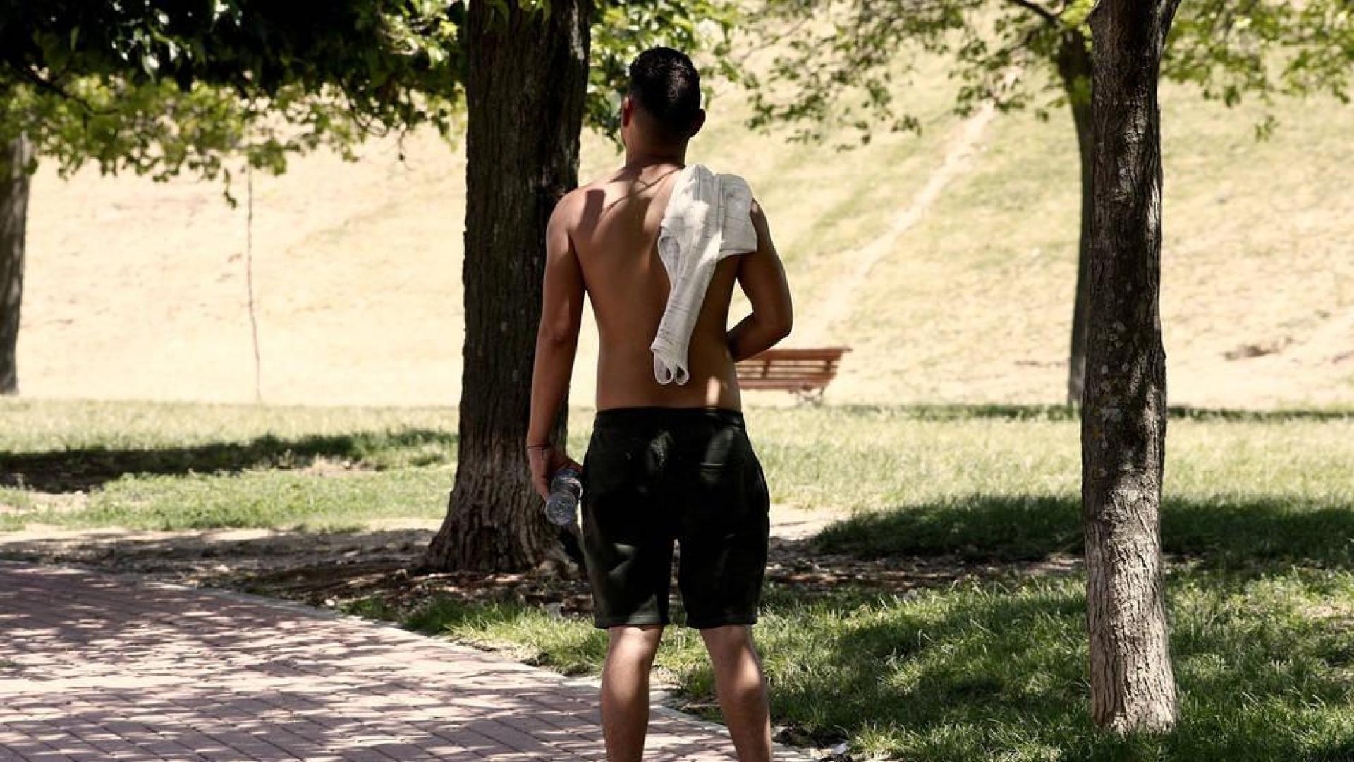 Un joven pasea sin camiseta a causa del calor.