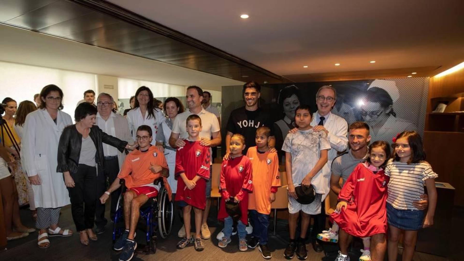 Personal de la Clínica Universidad de Navarra junto a jugadores, entrenador y presidente del  C.A. Osasuna, tras entregar las nuevas batas 'rojillas' a los niños ingresados.