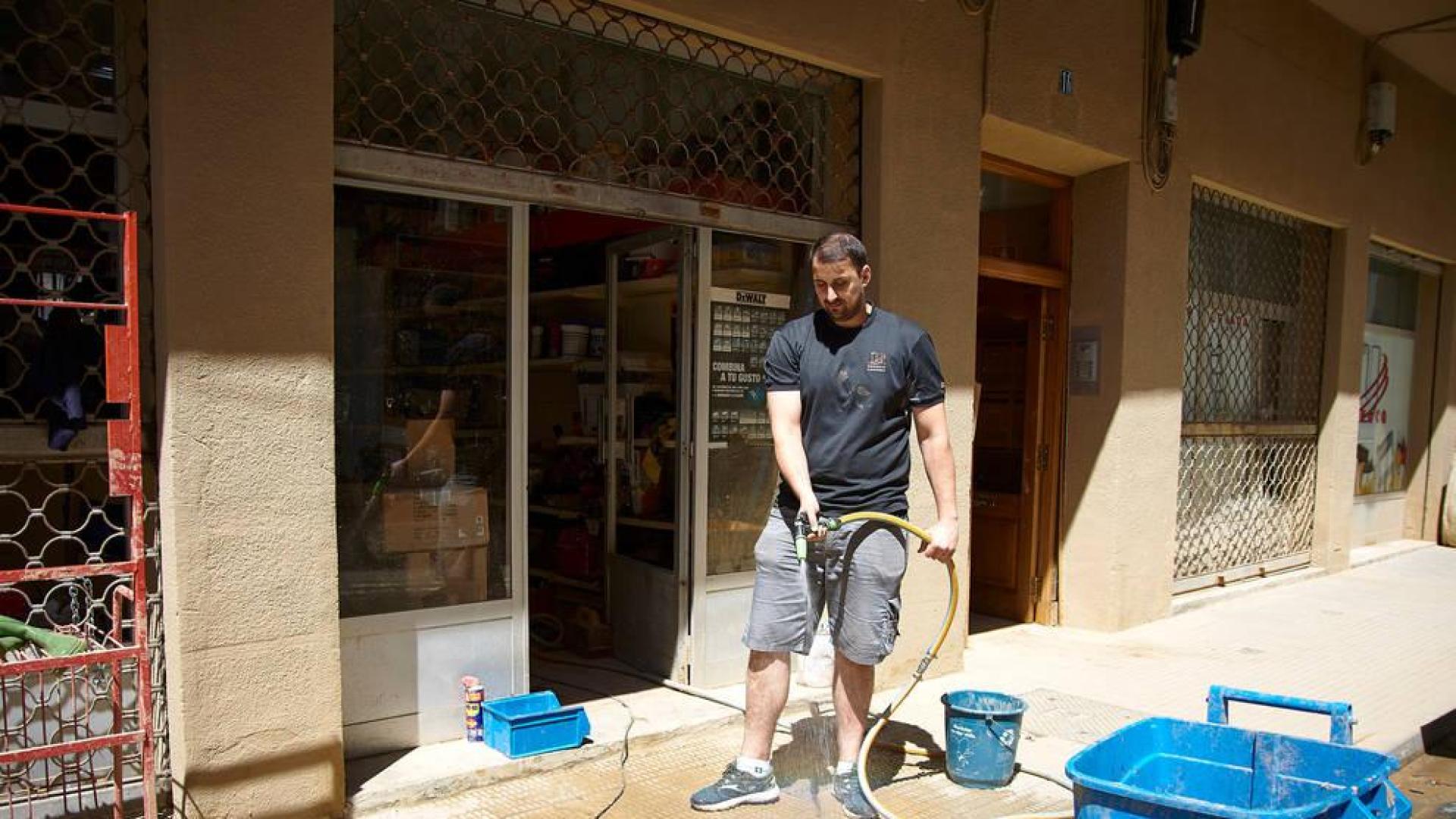 Un comerciante limpia las inmediaciones de su establecimiento tras las lluvias torrenciales del 8 de julio pasado