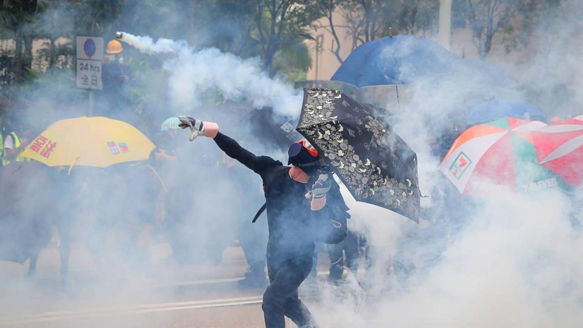Un protestante antigubernamental arroja un bote de gas a los policía.