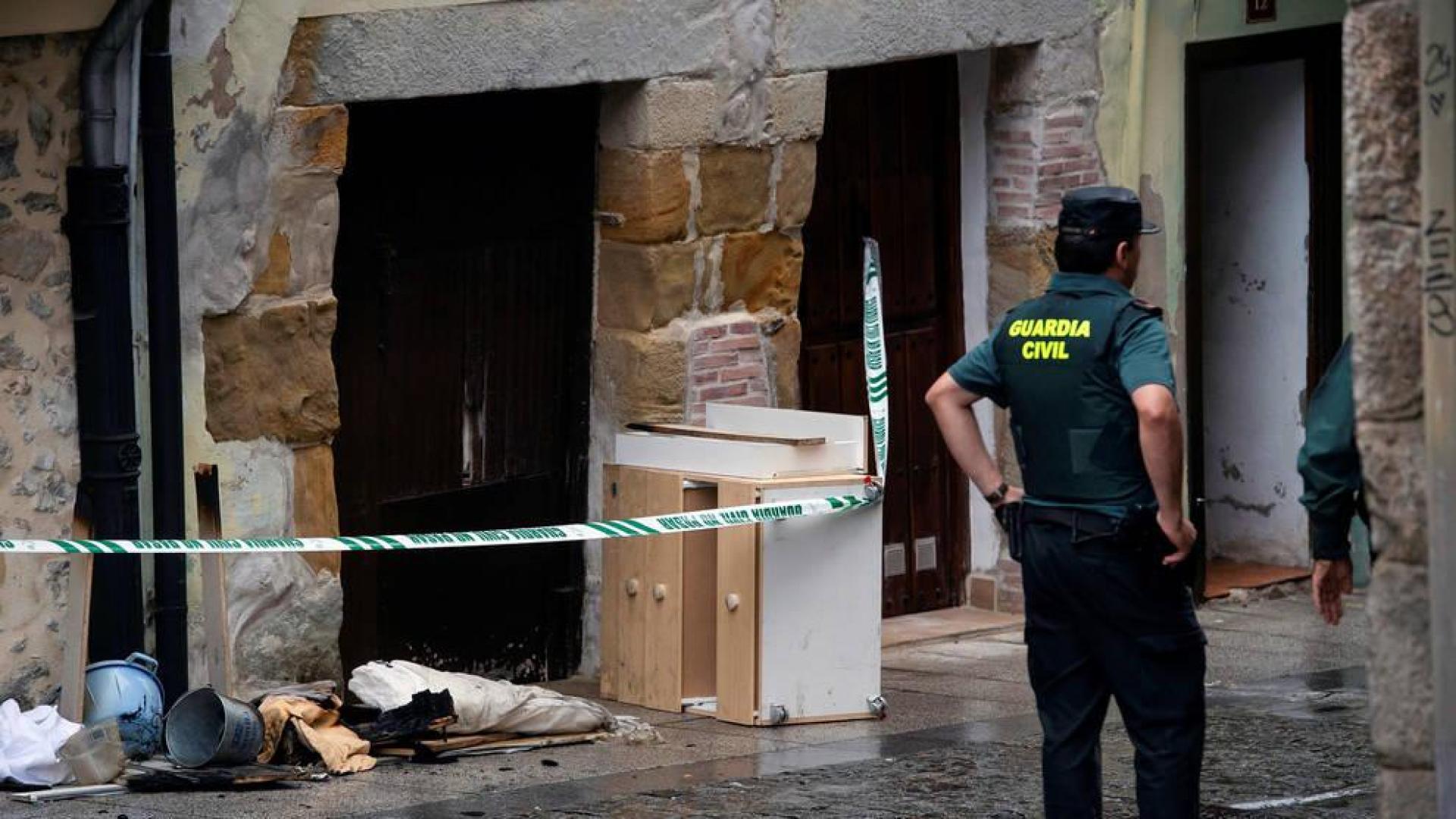 Agentes de la Guardia Civil junto a la vivienda de Laredo en la que han fallecido una mujer y su hija de 7 años a causa de un incendio.
