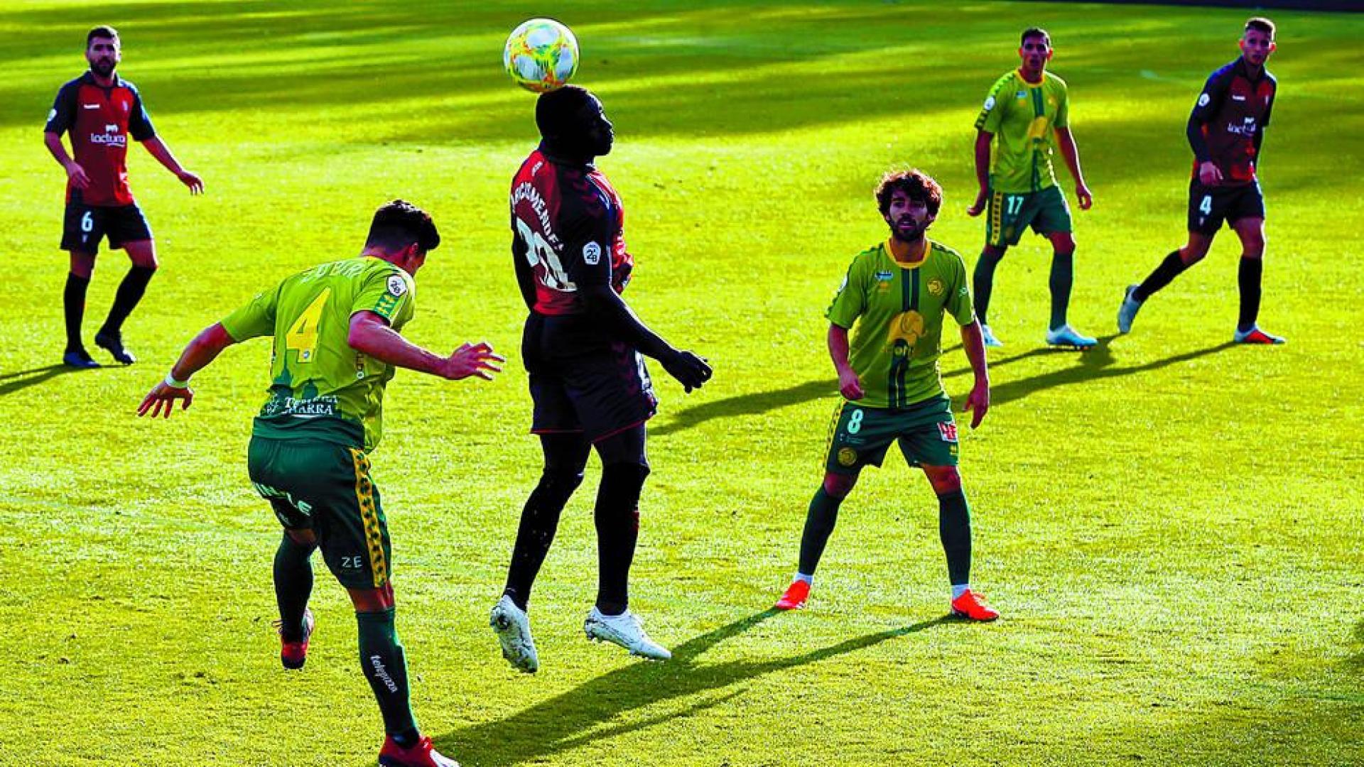 El jugador de Osasuna Promesas Marcos Mendes peina el balón entre los futbolistas de Unionistas Zubiri y Javi Navas, durante el partido de ayer en Tajonar.