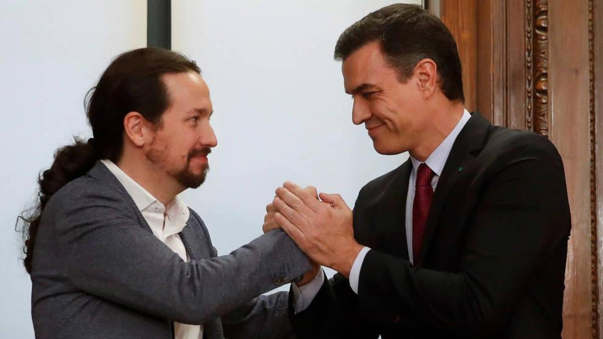 El candidato a la investidura, Pedro Sánchez (d), y el líder de Podemos, Pablo Iglesias (i), estrechan sus manos tras el acto de firma del acuerdo programático.