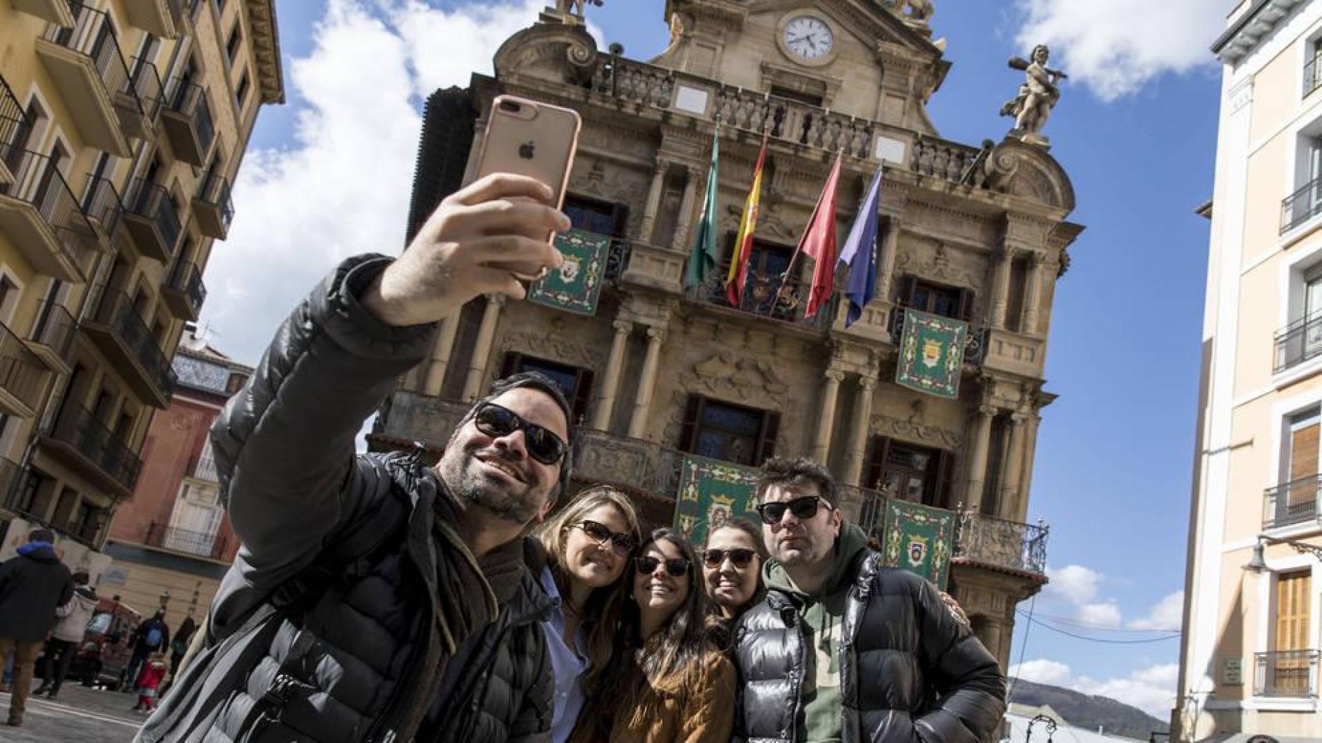 Unos turistas se hacen una foto delante del Ayuntamiento de Pamplona