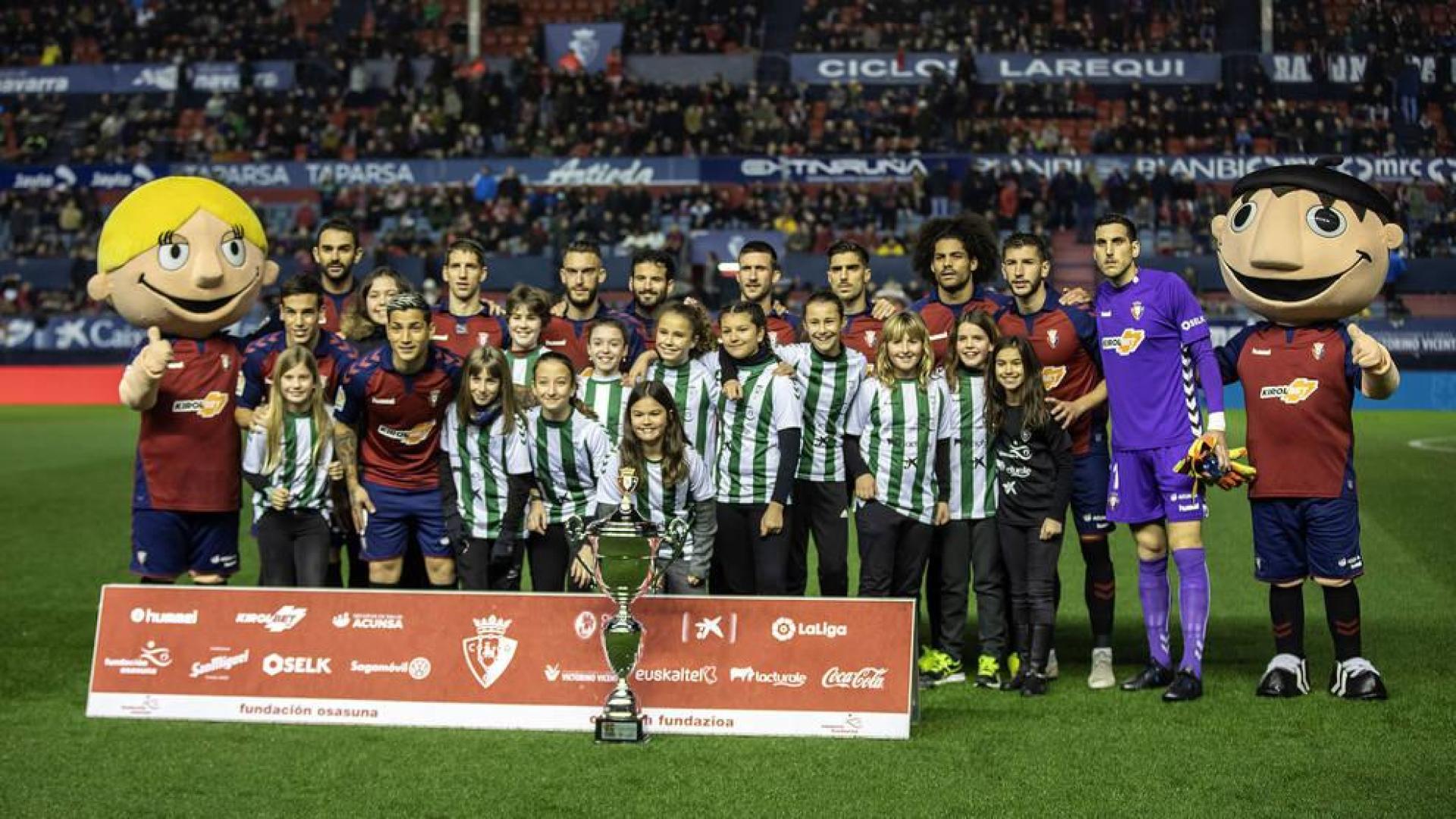 El once de Osasuna se fotografía con las jugadoras de Paz de Ziganda, campeonas del Interescolar.