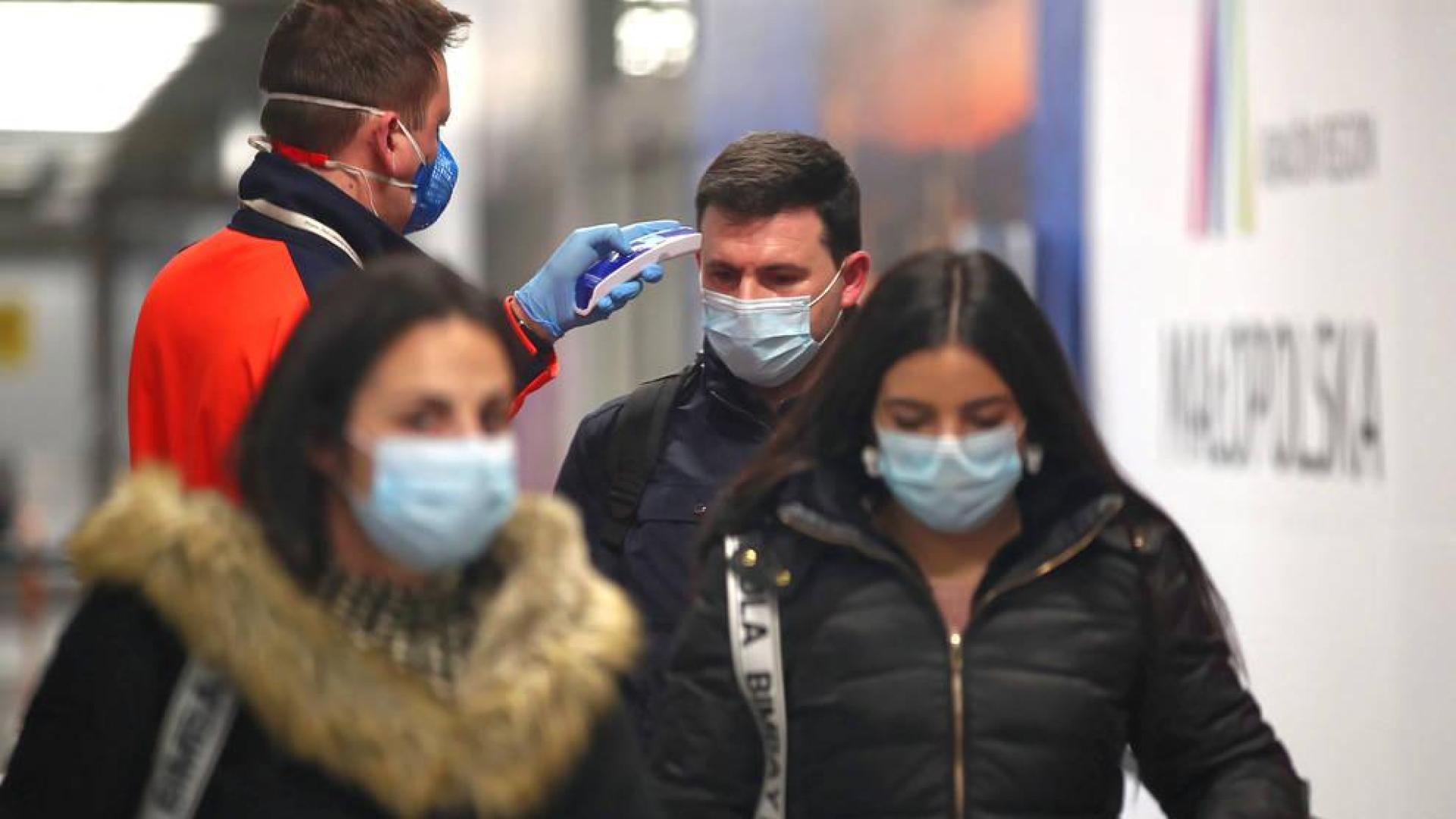 Un sanitario toma la temperatura a un joven en el aeropuerto de Cracovia.