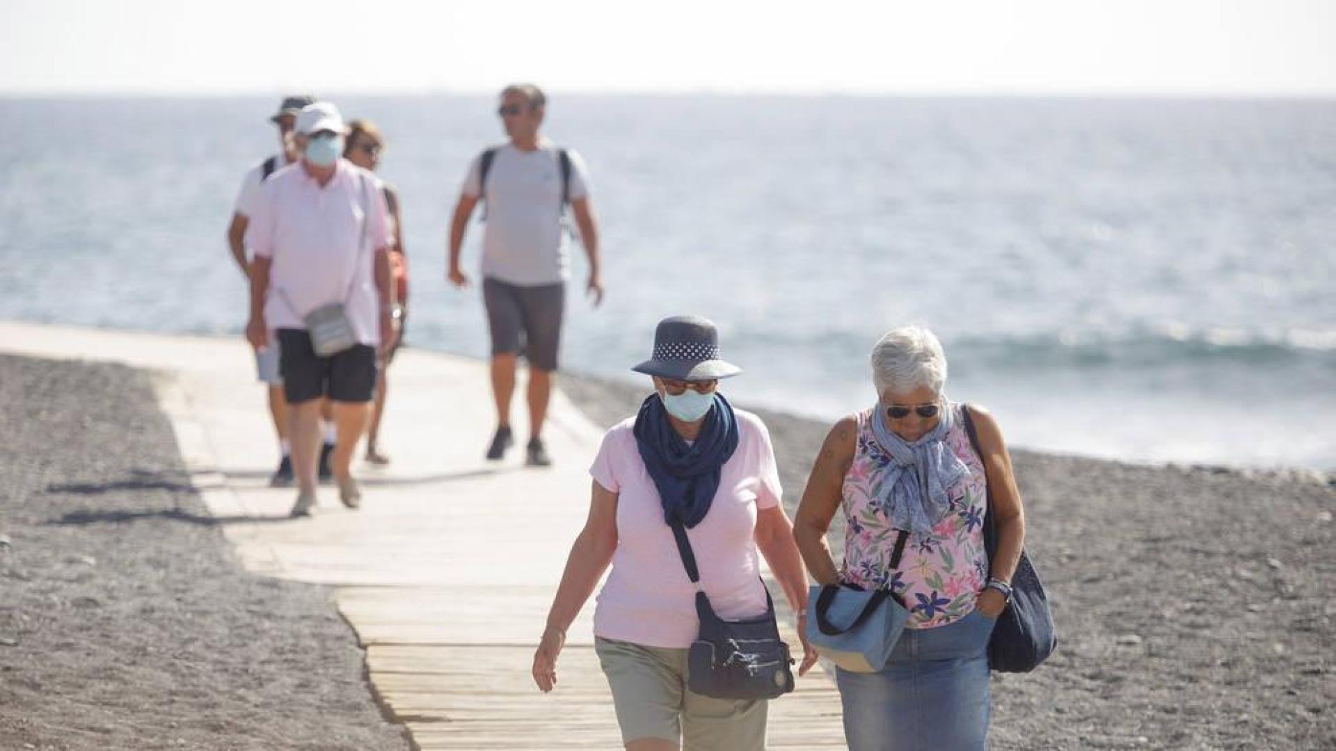 Varios turistas pasean este viernes por las inmediaciones del hotel en el que desde el pasado lunes permanecen incomunicados sus huéspedes y trabajadores al dar positivo en coronavirus cuatro de los que se alojaban en el centro turístico de Adeje, en el sur de Tenerife.