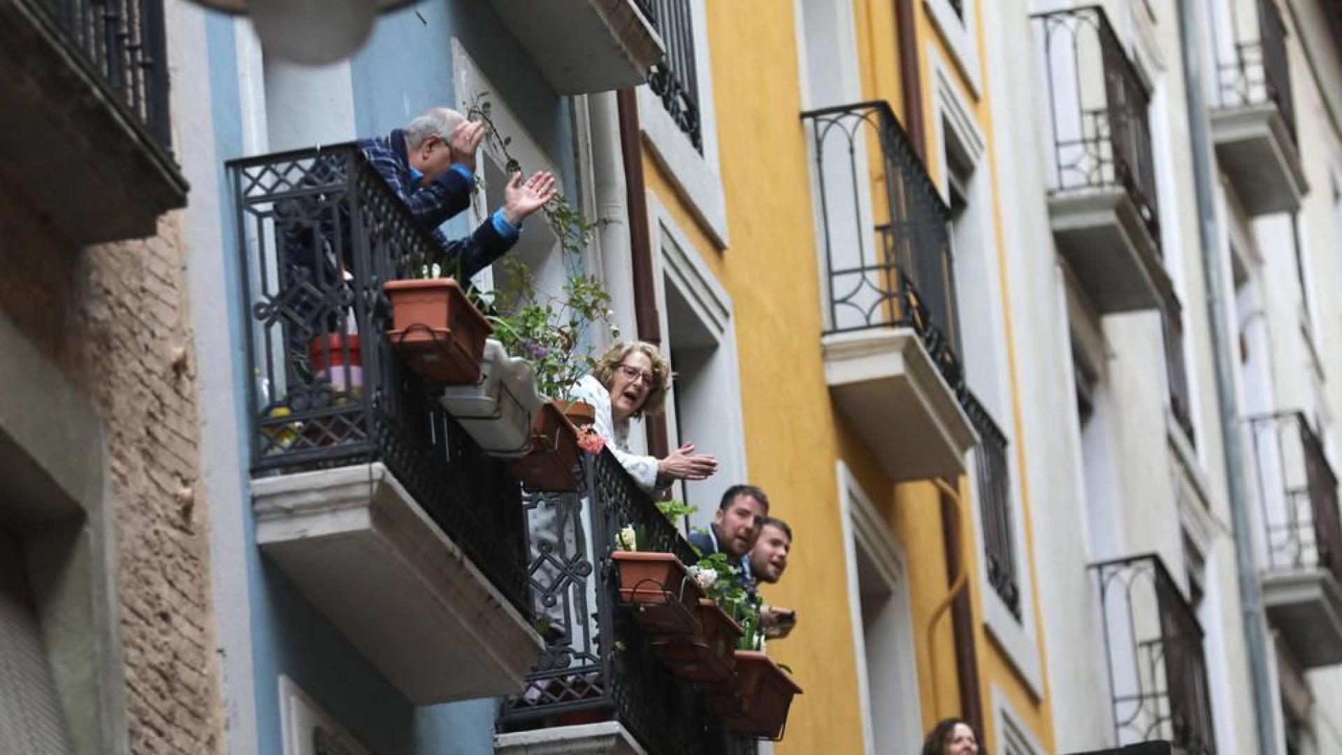 Varias personas, asomadas al balcón, entonan el Riau Riau en la bajada de Javier de Pamplona