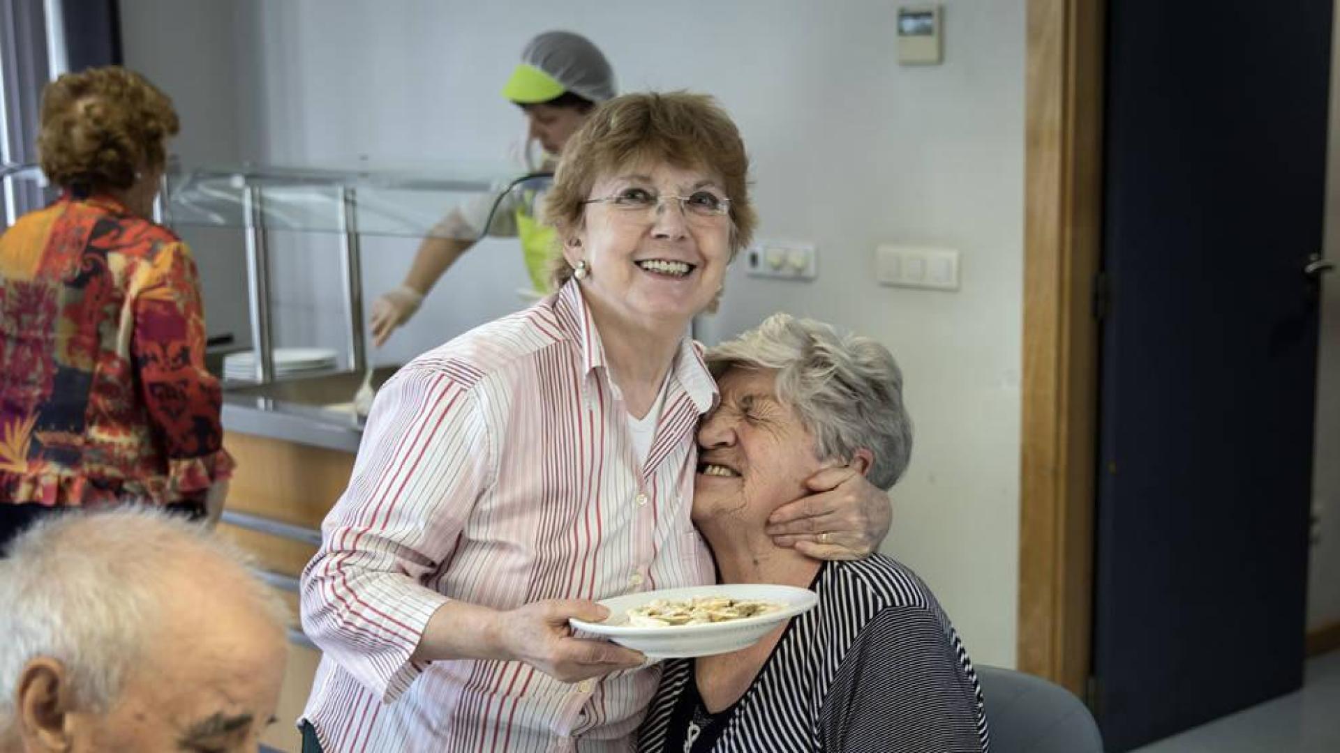 Gesto cariñoso entre dos de las usuarias del comedor del centro de mayores Oskia, en el barrio de San Juan.
