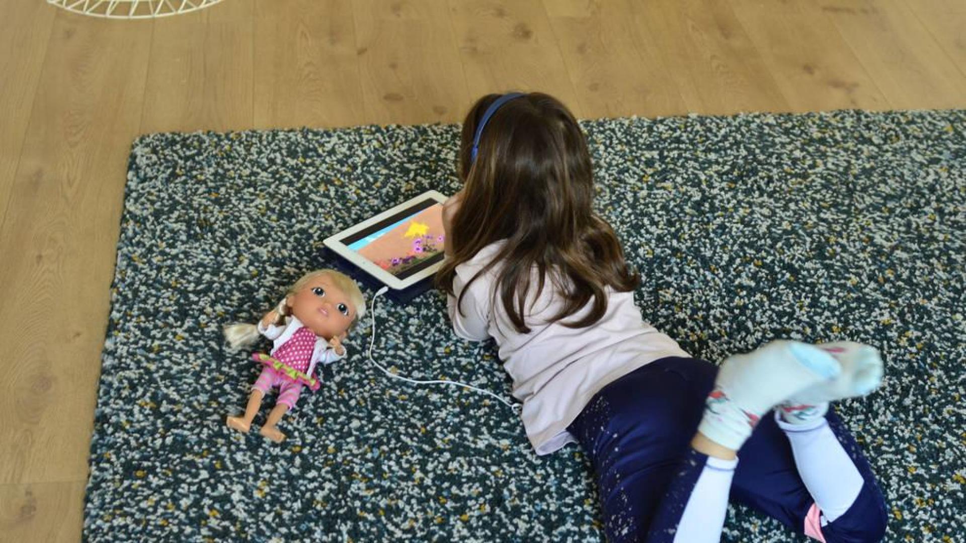 Una niña lee en el salón de su casa.