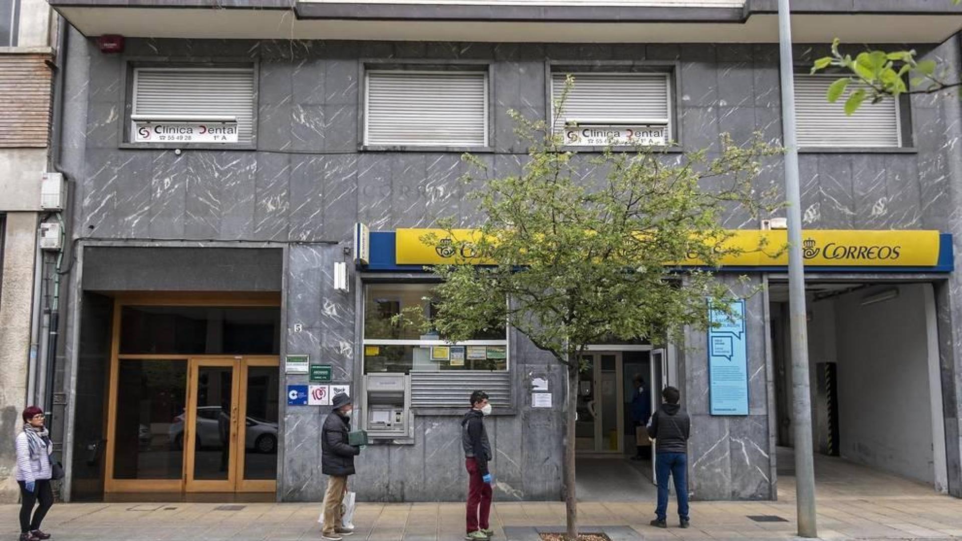 Varias personas esperan el martes su turno para acceder a Correos en un paseo de la Inmaculada sin apenas tráfico estos días.