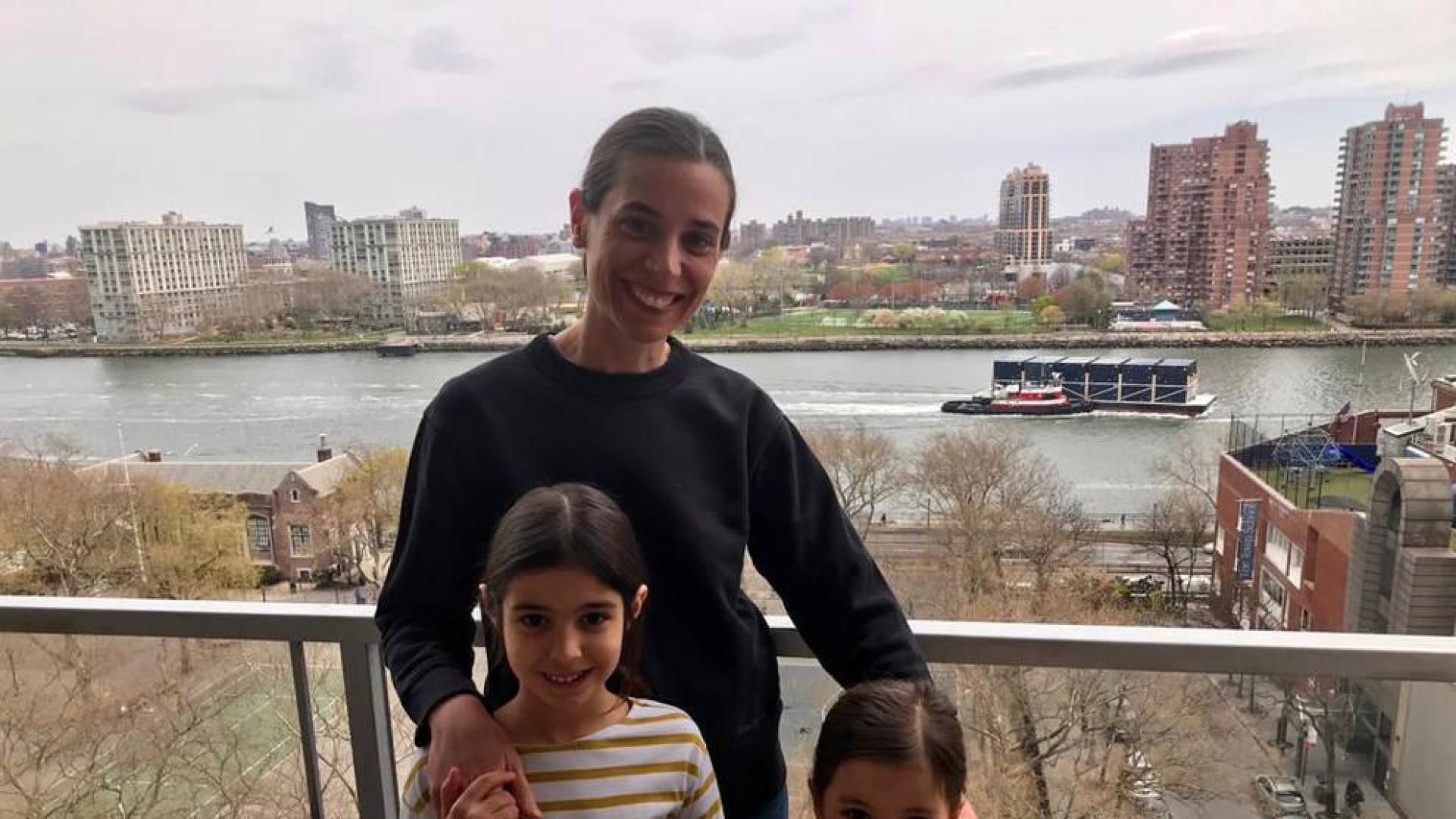 La adrianesa Amaya Guillermo Jiménez con sus dos hijas, Julia y Manuela, en el balcón de su casa de Manhattan, con el East River detrás.