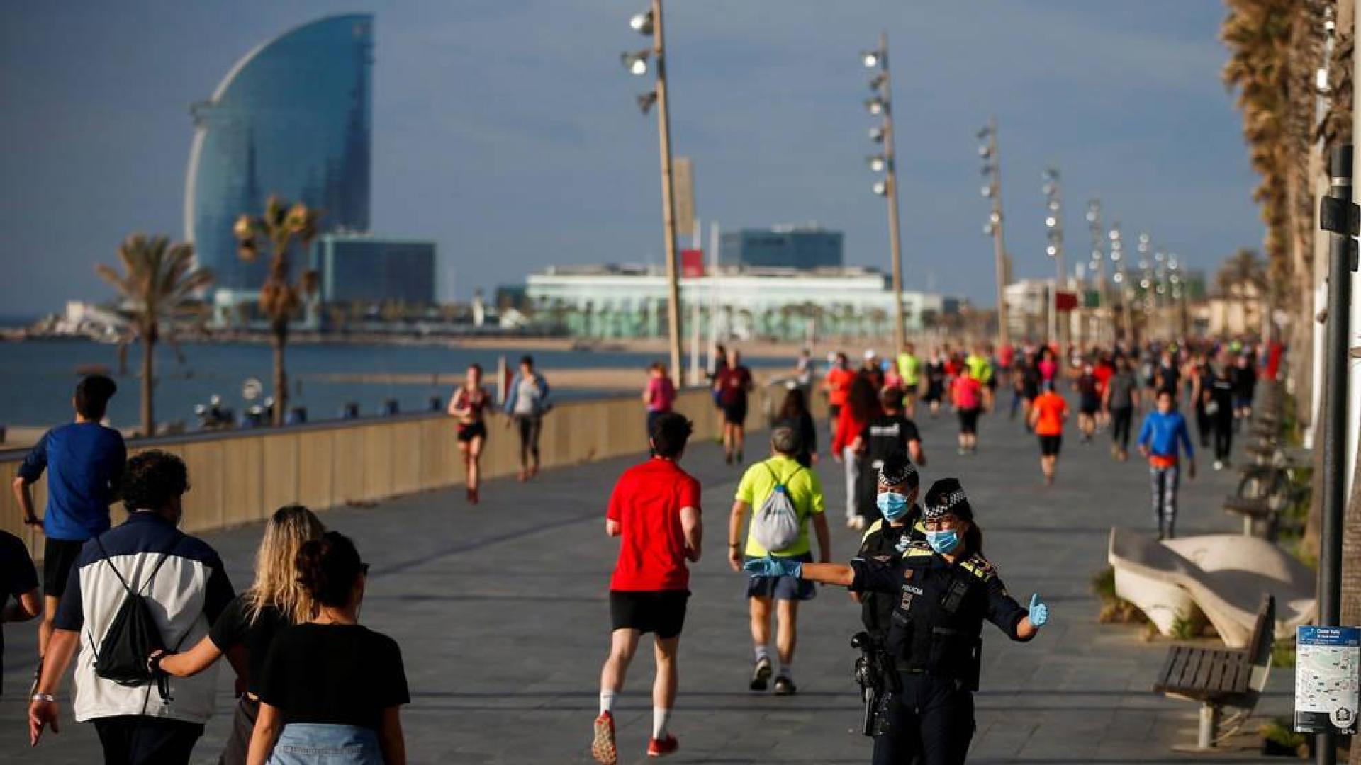 Policías municipales dan indicaciones a los ciudadanos que dan un paseo o hacen ejercicio por el Paseo Marítimo de Barcelona