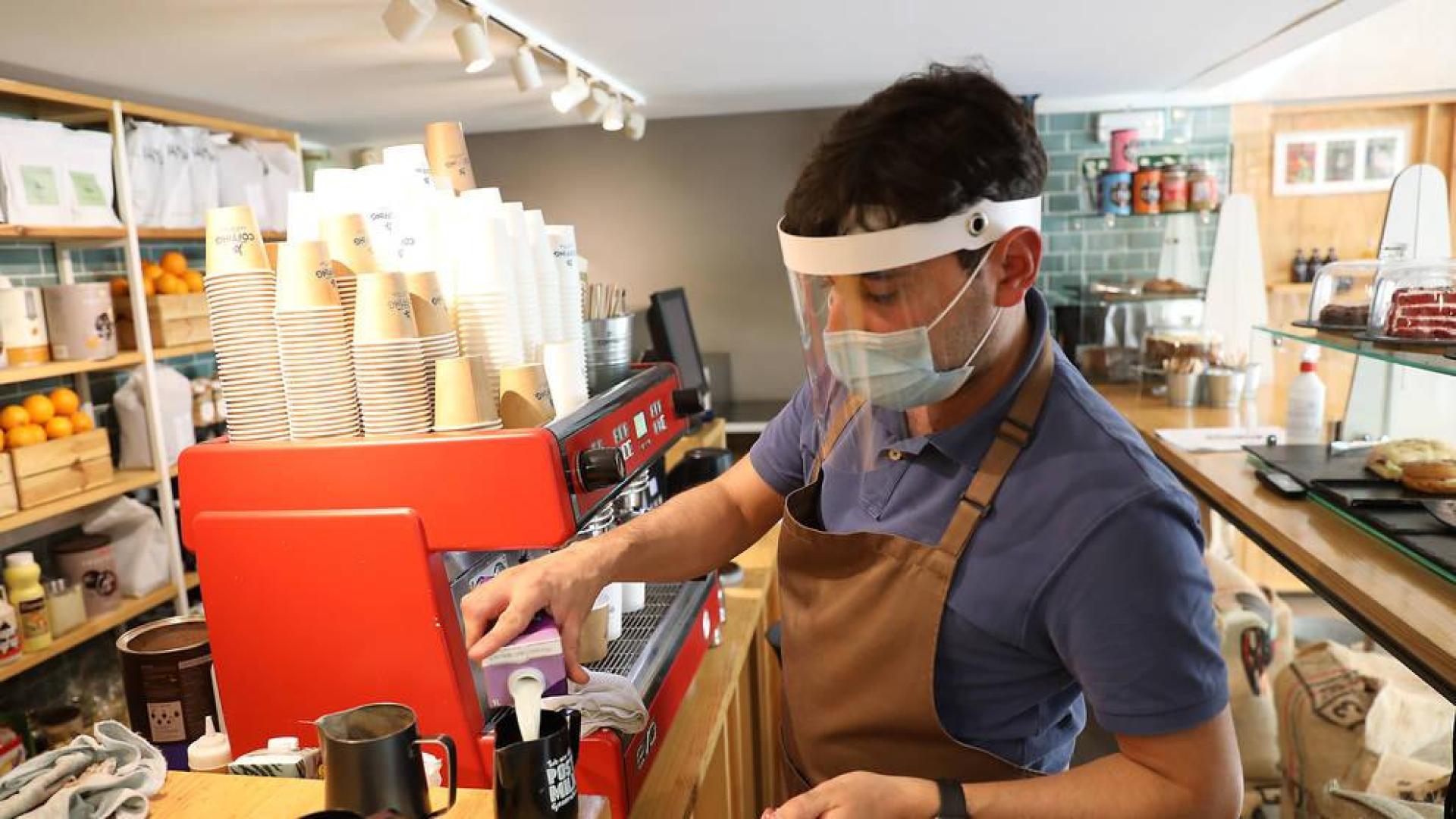 Manuel Spucches, con pantalla y mascarilla, sirve un café.