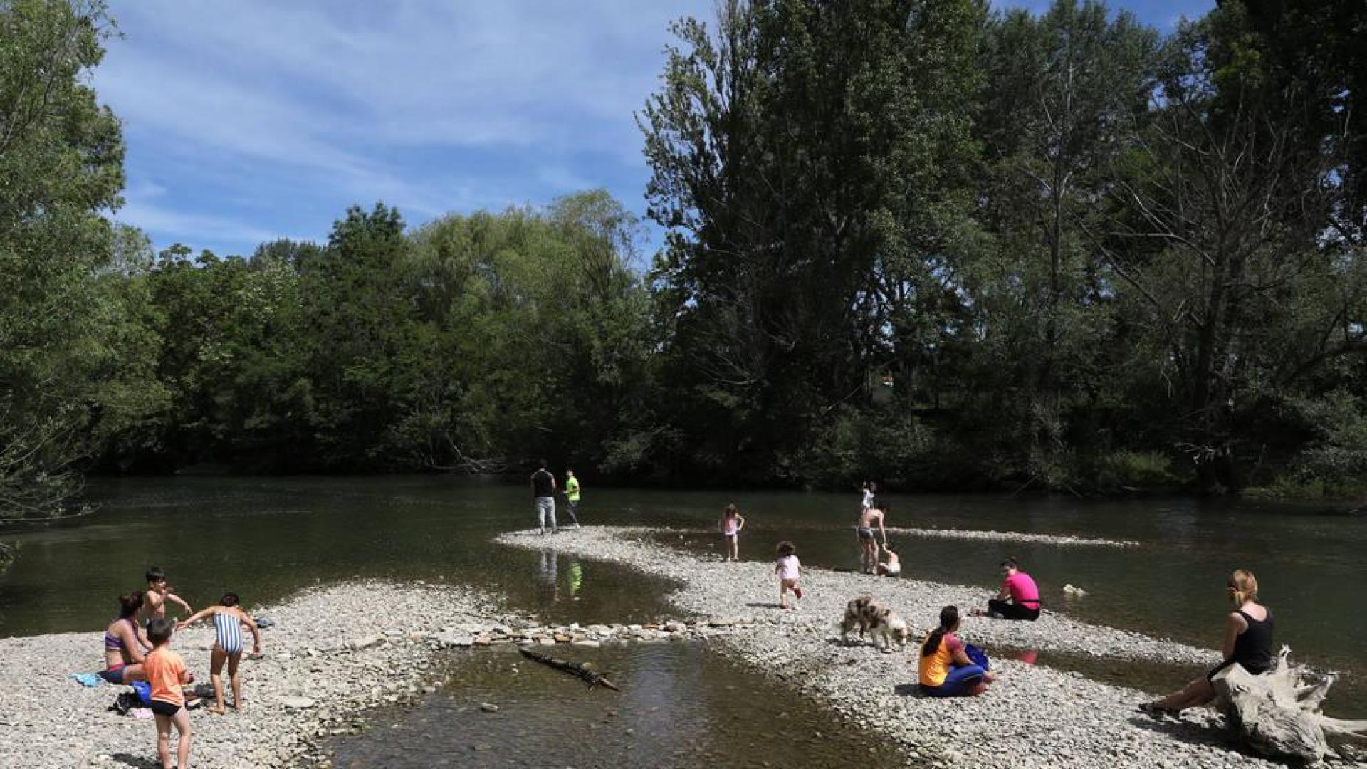 Disfrutar del sol e incluso refrescarse a la orilla del río Arga alivió del calor a decenas de personas.