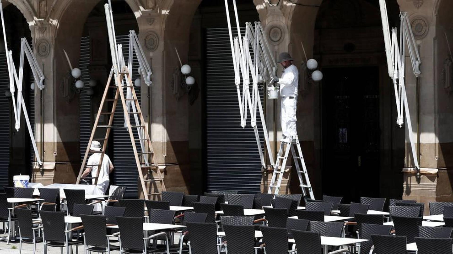 Unos trabajadores limpian una terraza en la Plaza del Castillo de Pamplona.