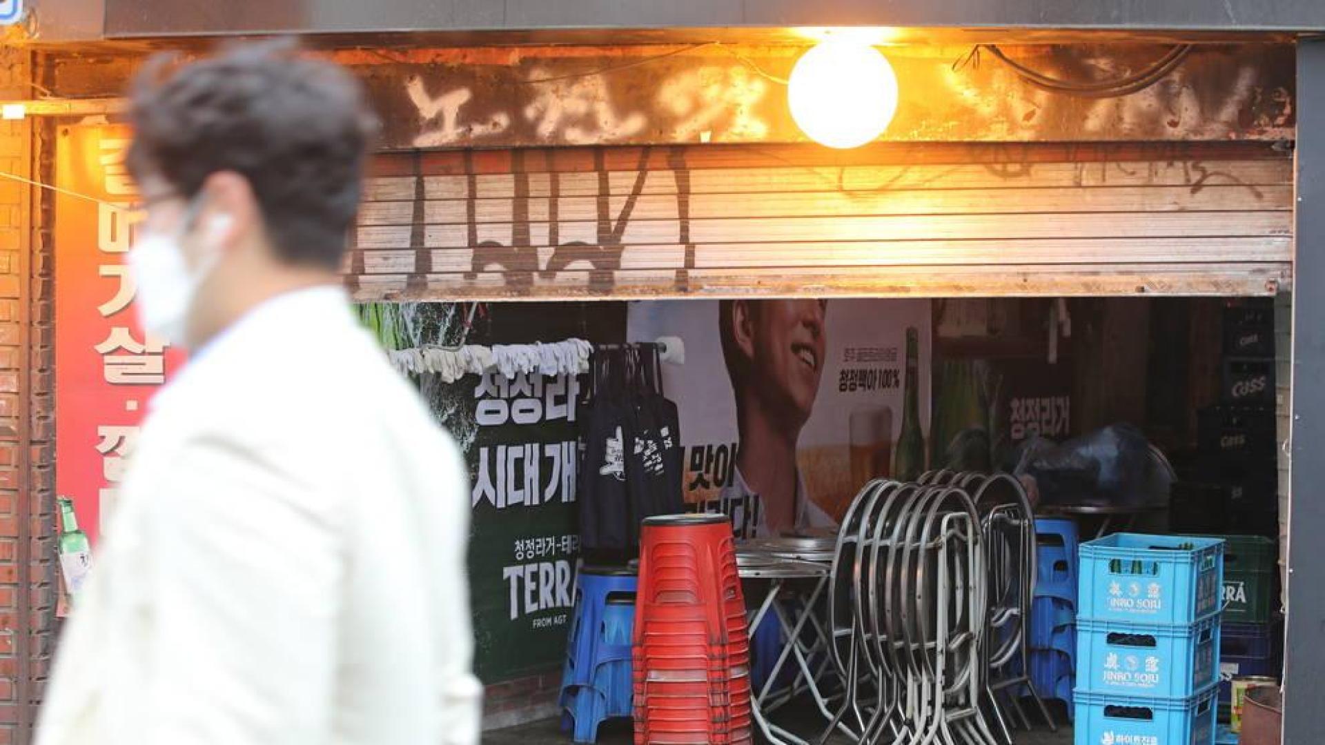 Un hombre pasa por delante de un bar cerrado en Seúl.
