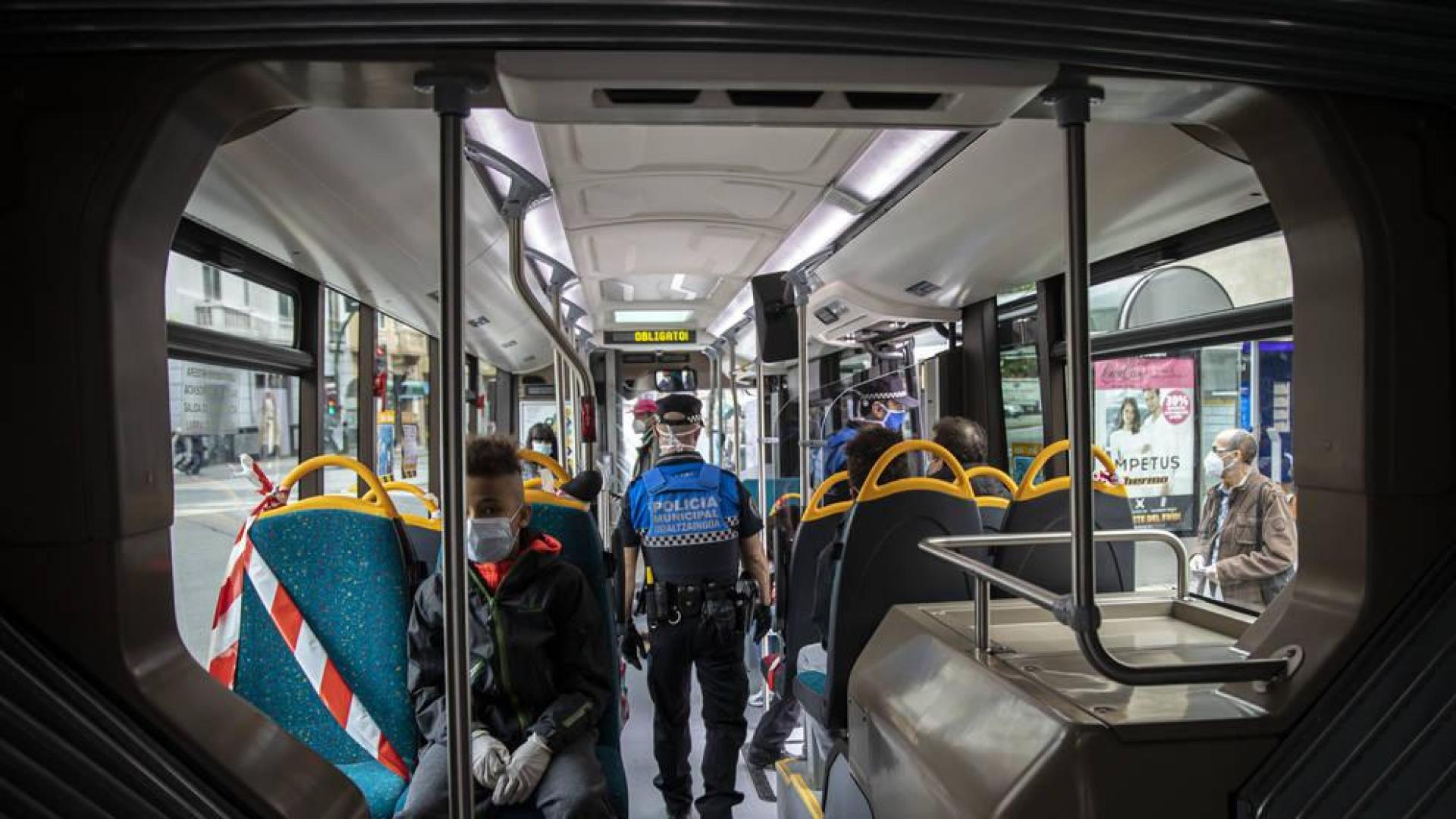 Dos policías municipales vigilan que la gente lleve mascarilla dentro del transporte público.