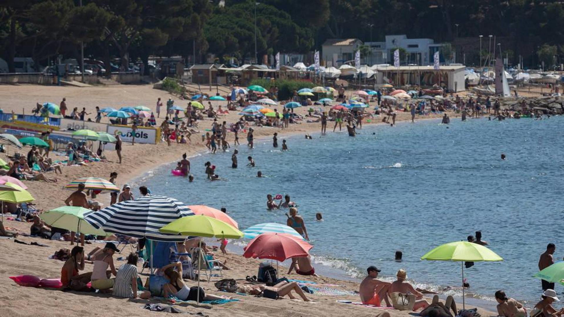 Varios bañistas se refrescan en la playa de Sant Feliu de Guixols.