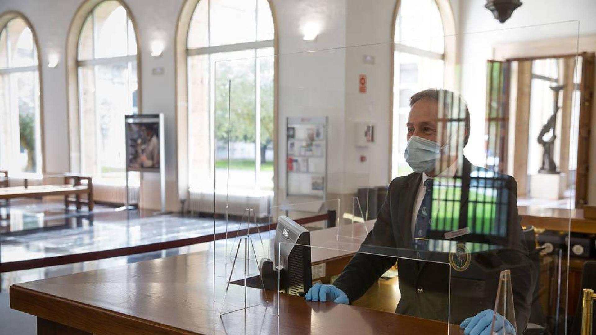 Uno de los bedeles de la Universidad, con mascarilla y detrás de la mampara que se ha colocado en el acceso al edificio Central.