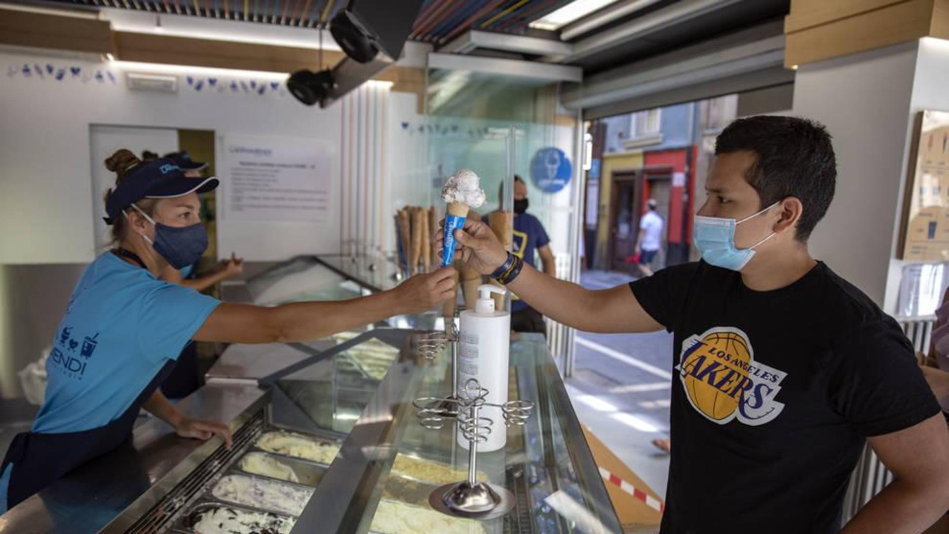 Varias personas comen helados, en cucurucho, en tarrina o en corte por las calles de Pamplona pese a la incomodidad de las mascarillas.