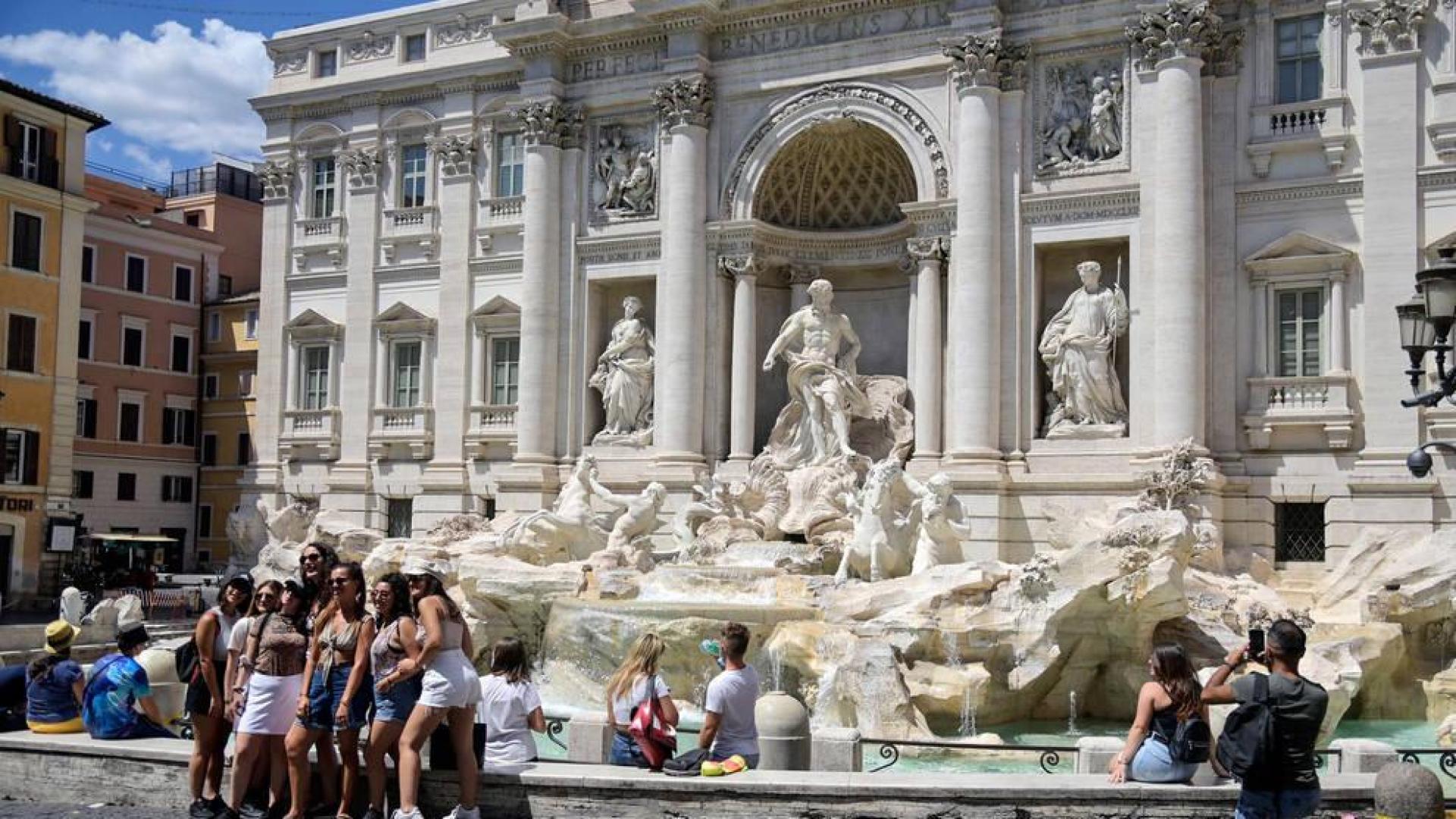 Varios turistas se fotografían en la Fontana de Trevi con mascarilla