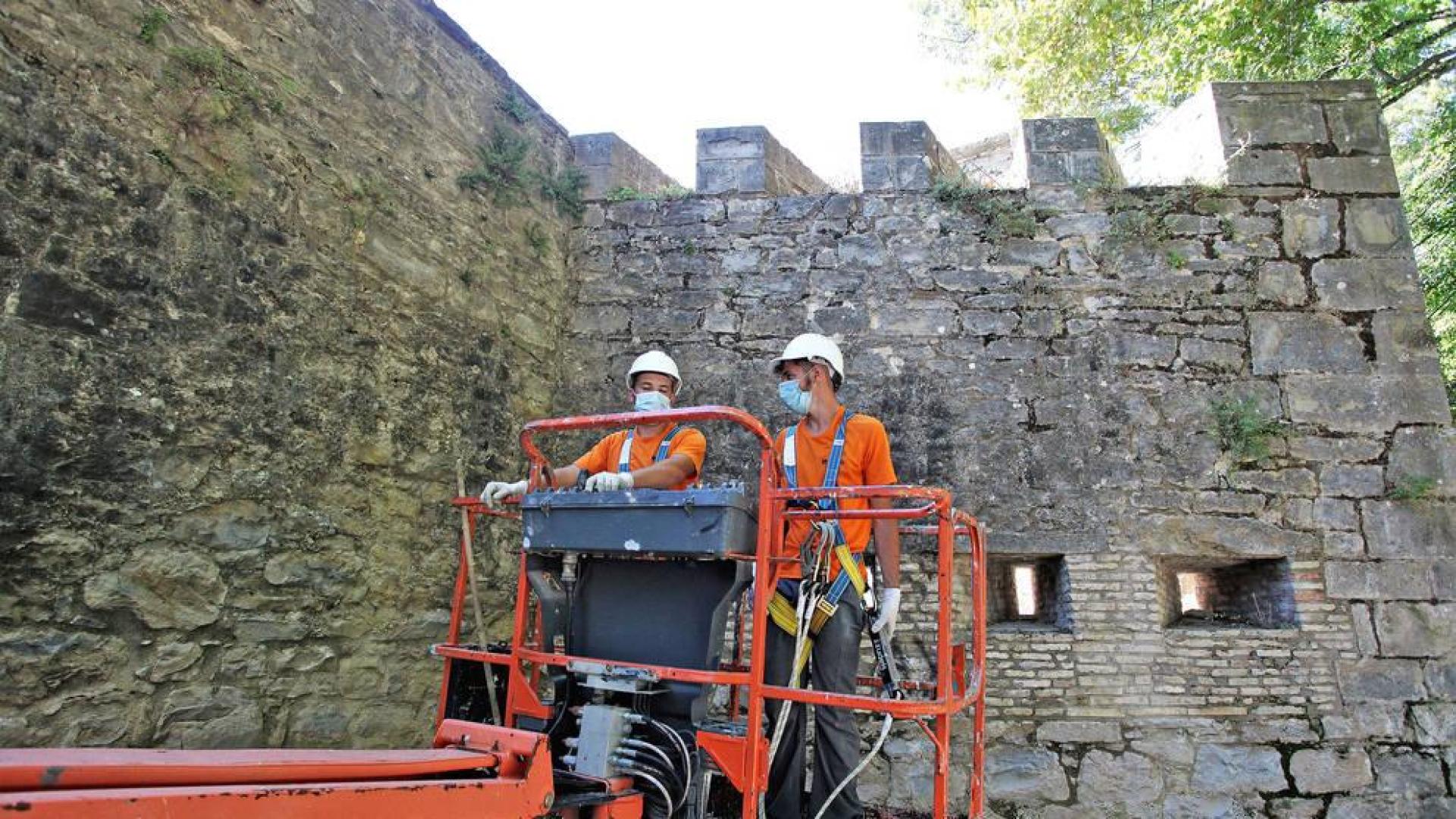 Dos operarios de Leache mueven el vehículo para retirar las malas hierbas de las cañoneras y merlones del fortín de San Bartolomé.