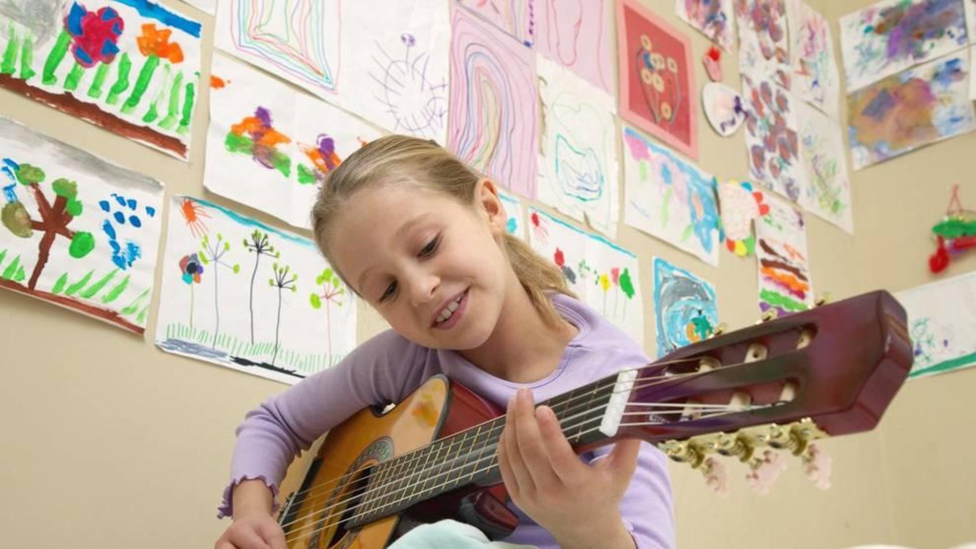 Una niña toca la guitarra en una clase.