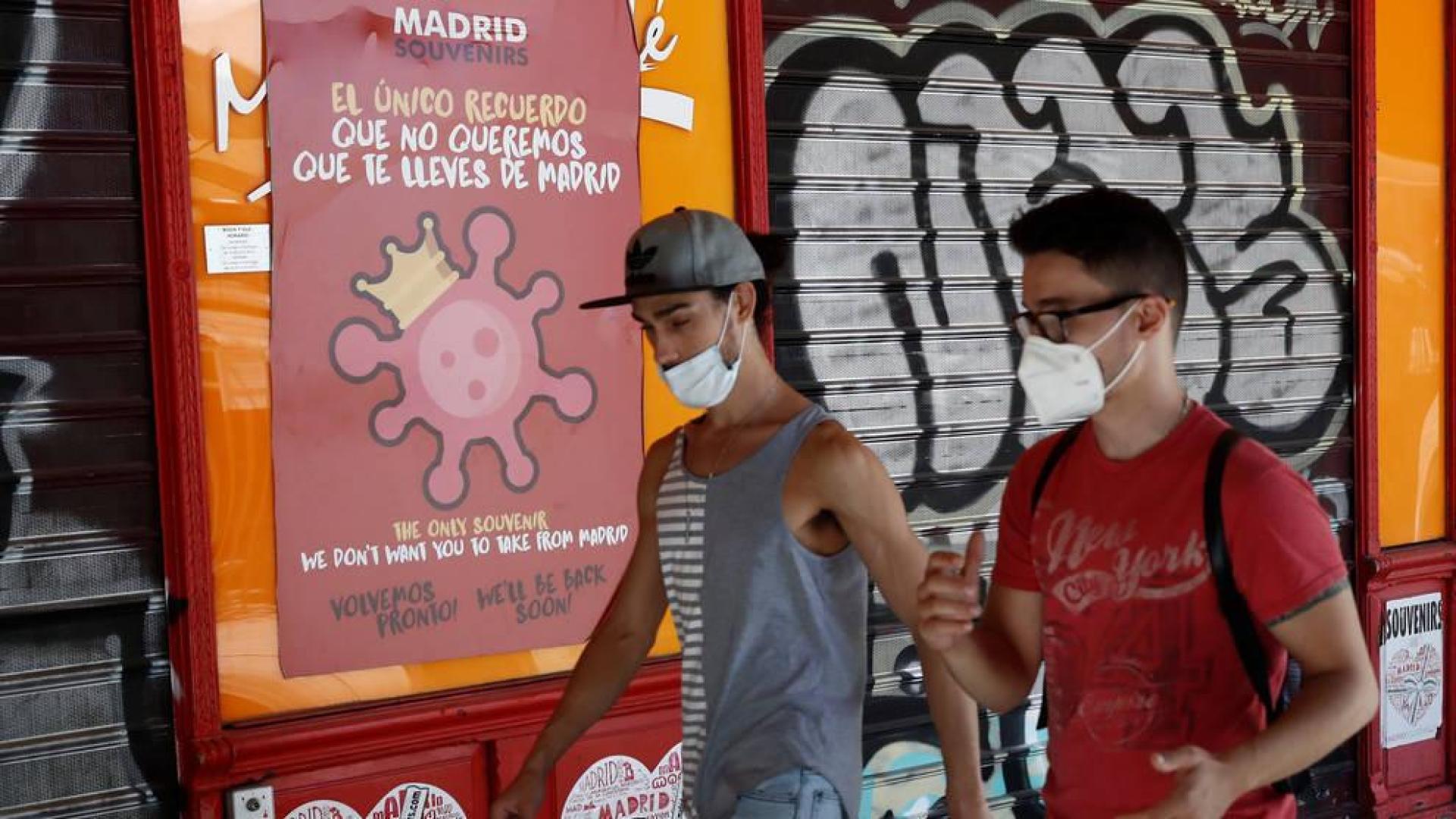Dos jóvenes pasean con mascarilla por una calle de Madrid