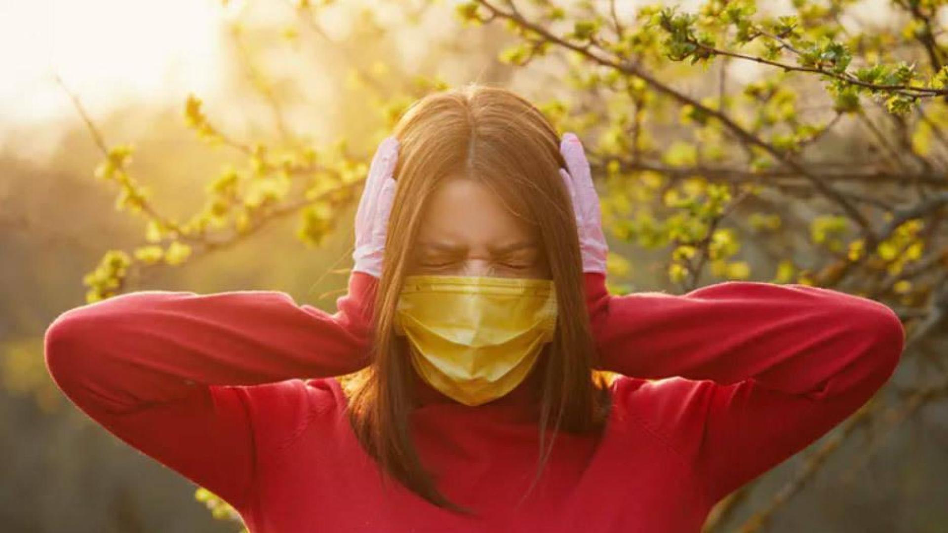 Una mujer con mascarilla se tapa los oídos.