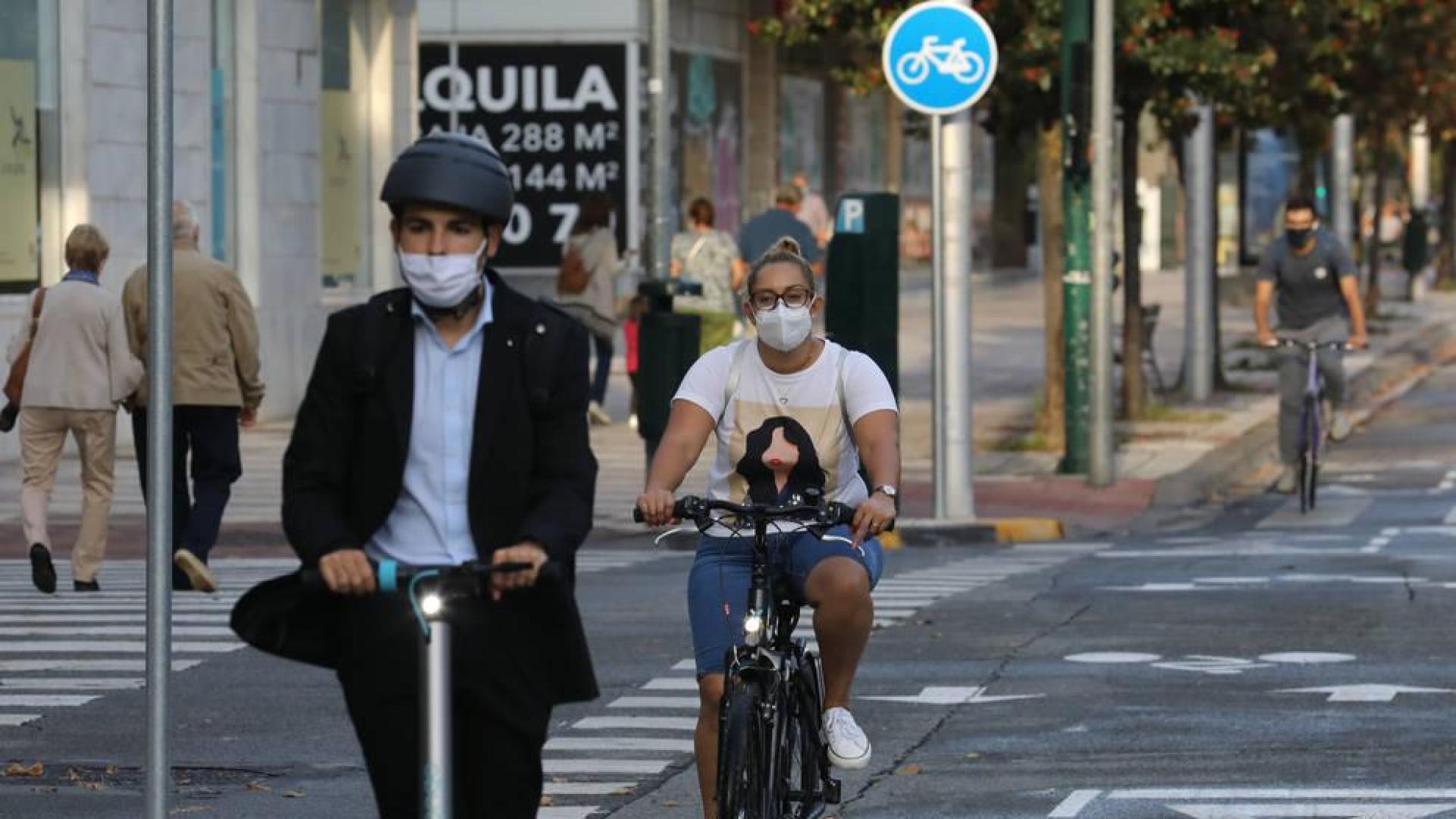 Un ciclista y un patín eléctrico recorren la avenida de Bayona.