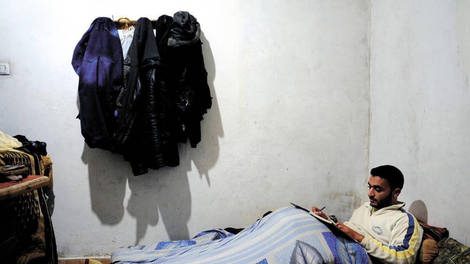 Durante el invierno, Shaman Alwawi, de 24 años, estudia bajo las mantas para protegerse del frío en casa. No tienen fuel suficiente para calentarse.