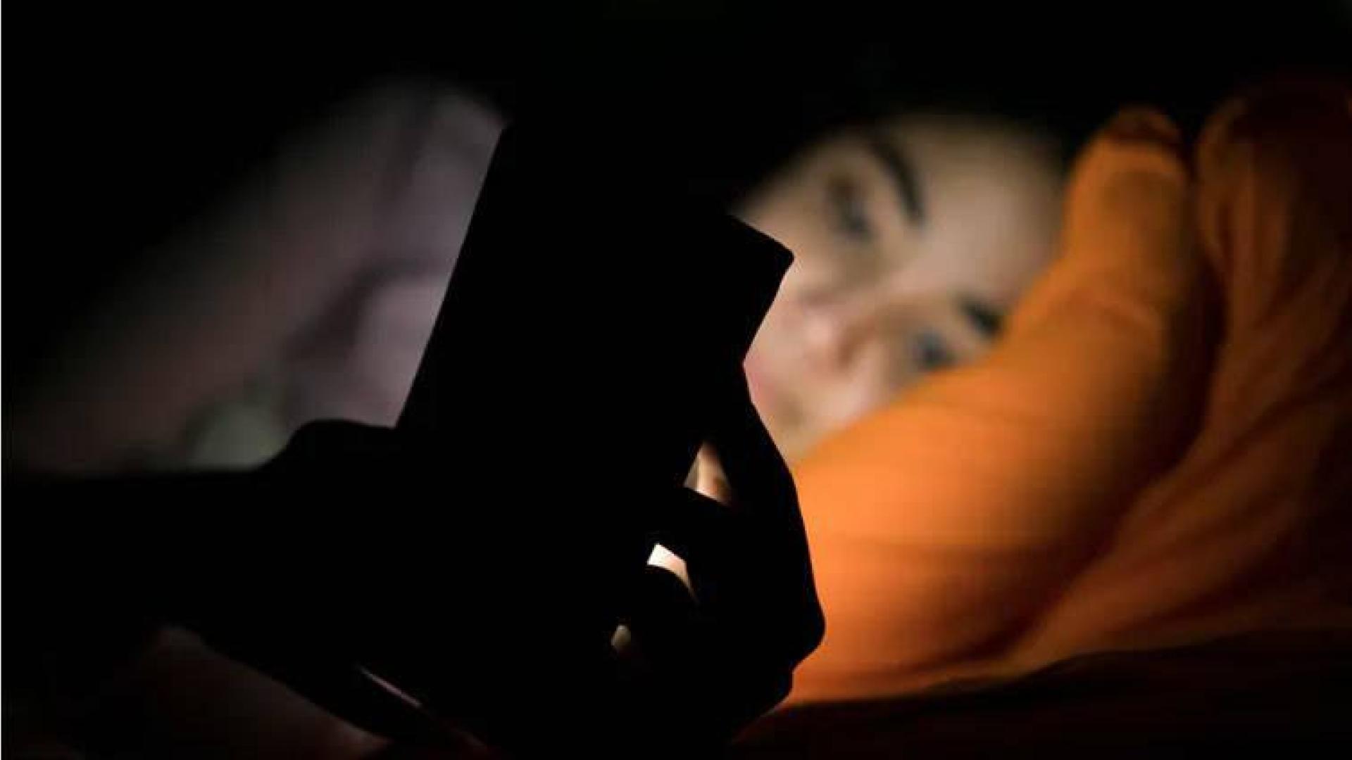 Una persona, con un móvil en la cama.