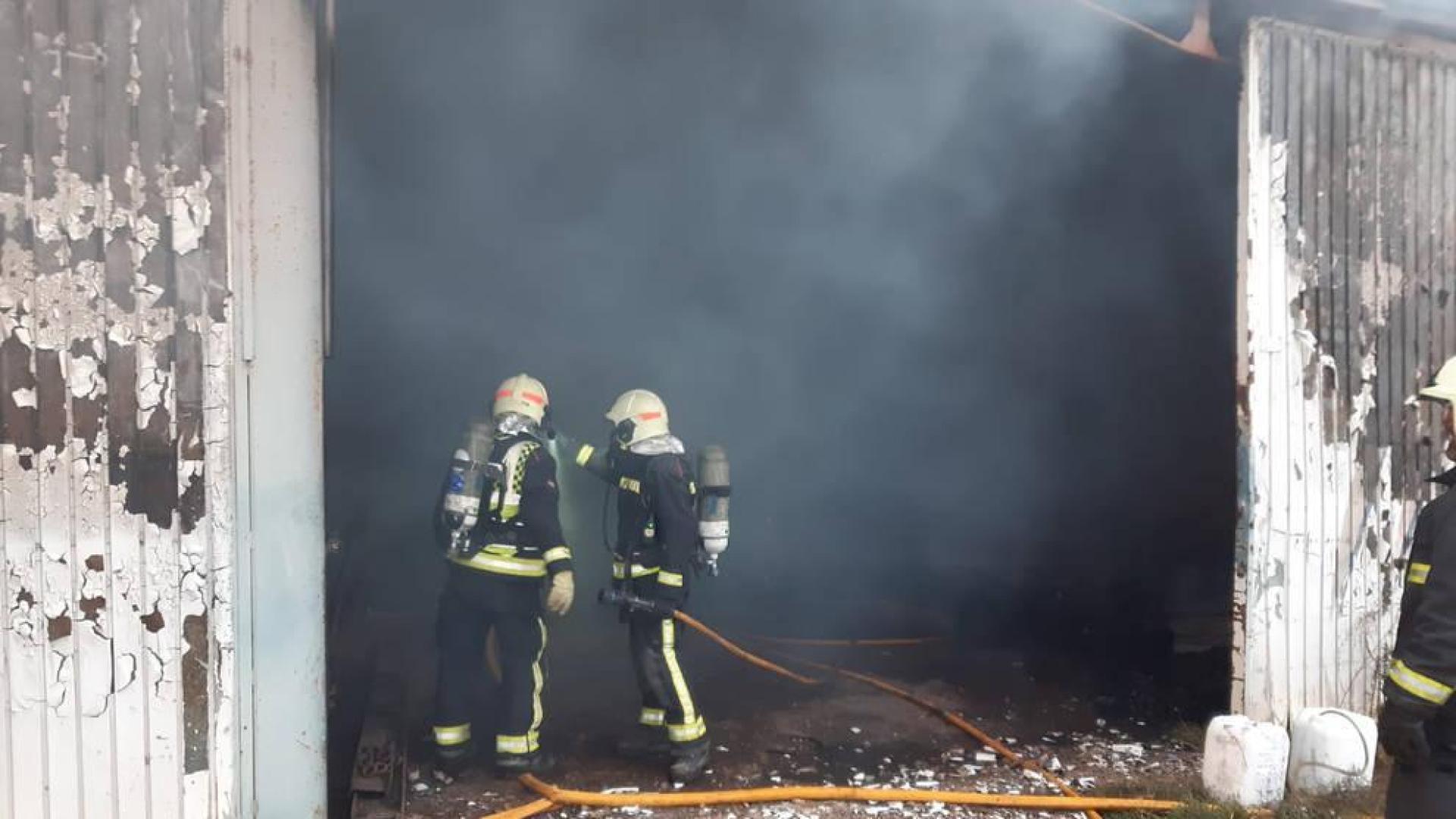 Dos bomberos, en la puerta de la nave que ha ardido.