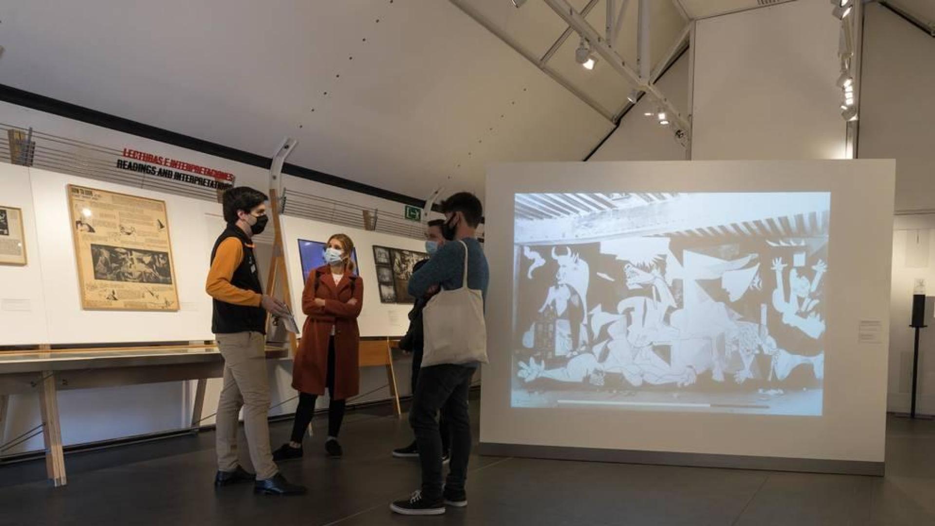 Asistentes a la inauguración de la muestra junto a una reproducción del 'Guernica' de Picasso.