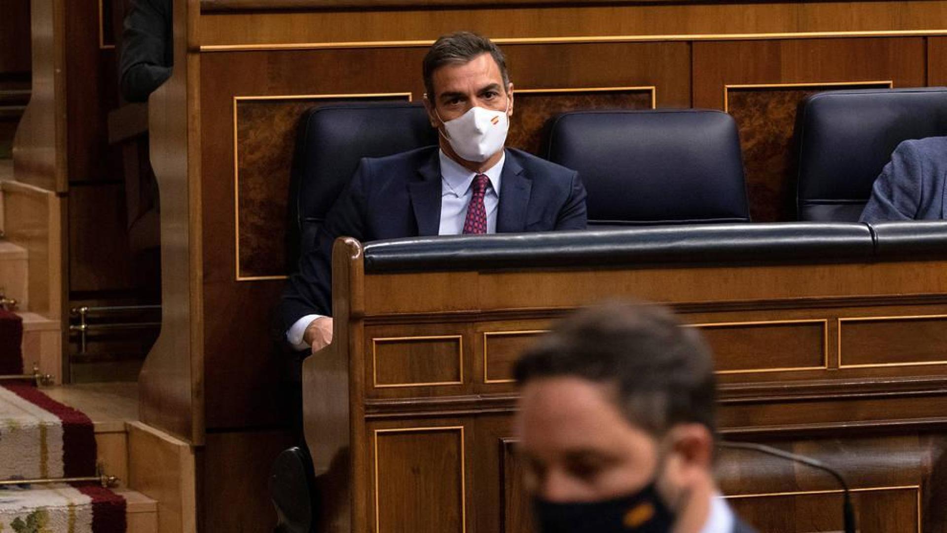 Santiago Abascal se acerca a la tribuna ante la mirada de Pedro Sánchez.