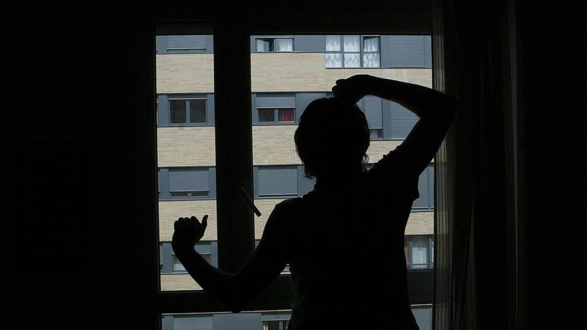 Un hombre mira por la ventana de su dormitorio.