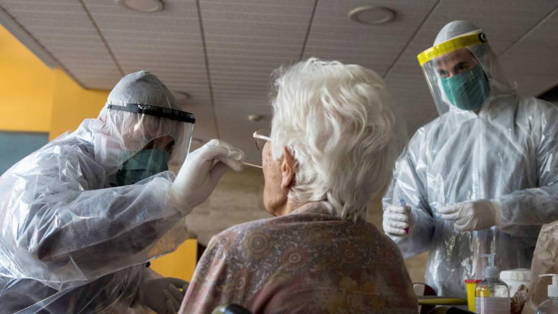 Varios sanitarios realizan la prueba del coronavirus a una anciana.