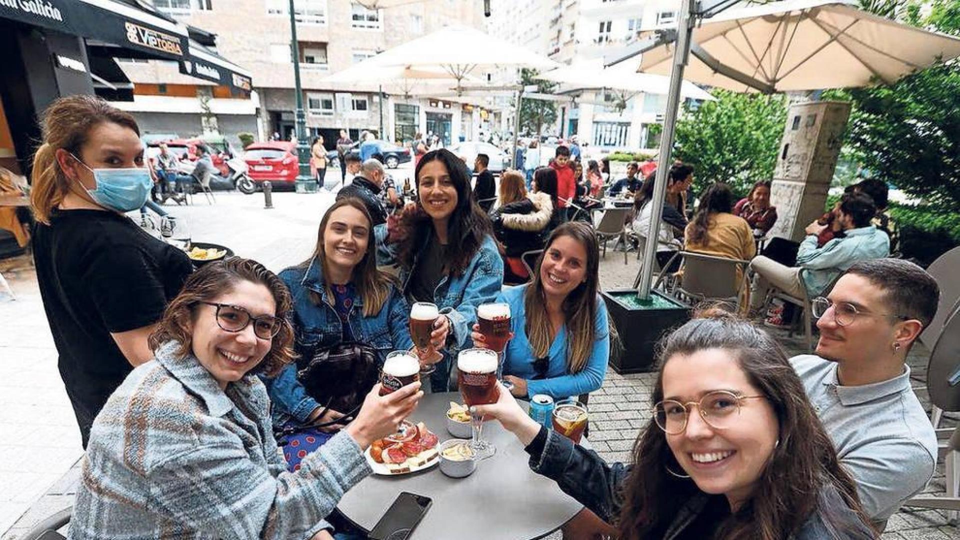 Un grupo de jóvenes celebra con cerveza y sin mascarilla en una terraza de un bar gallego.