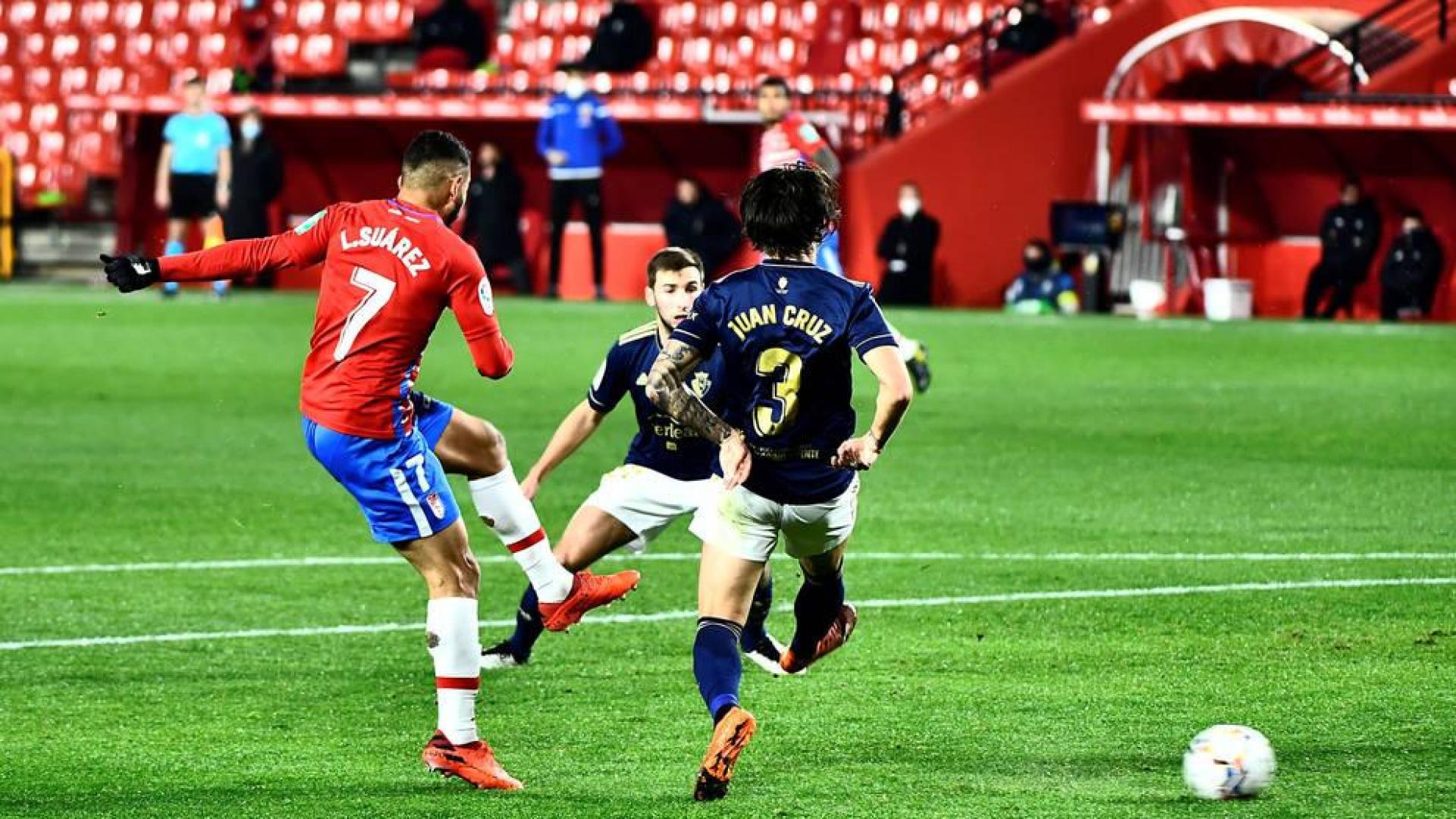 El delantero colombiano del Granada Luis Suárez golpea el balón ante dos rivales de Osasuna,