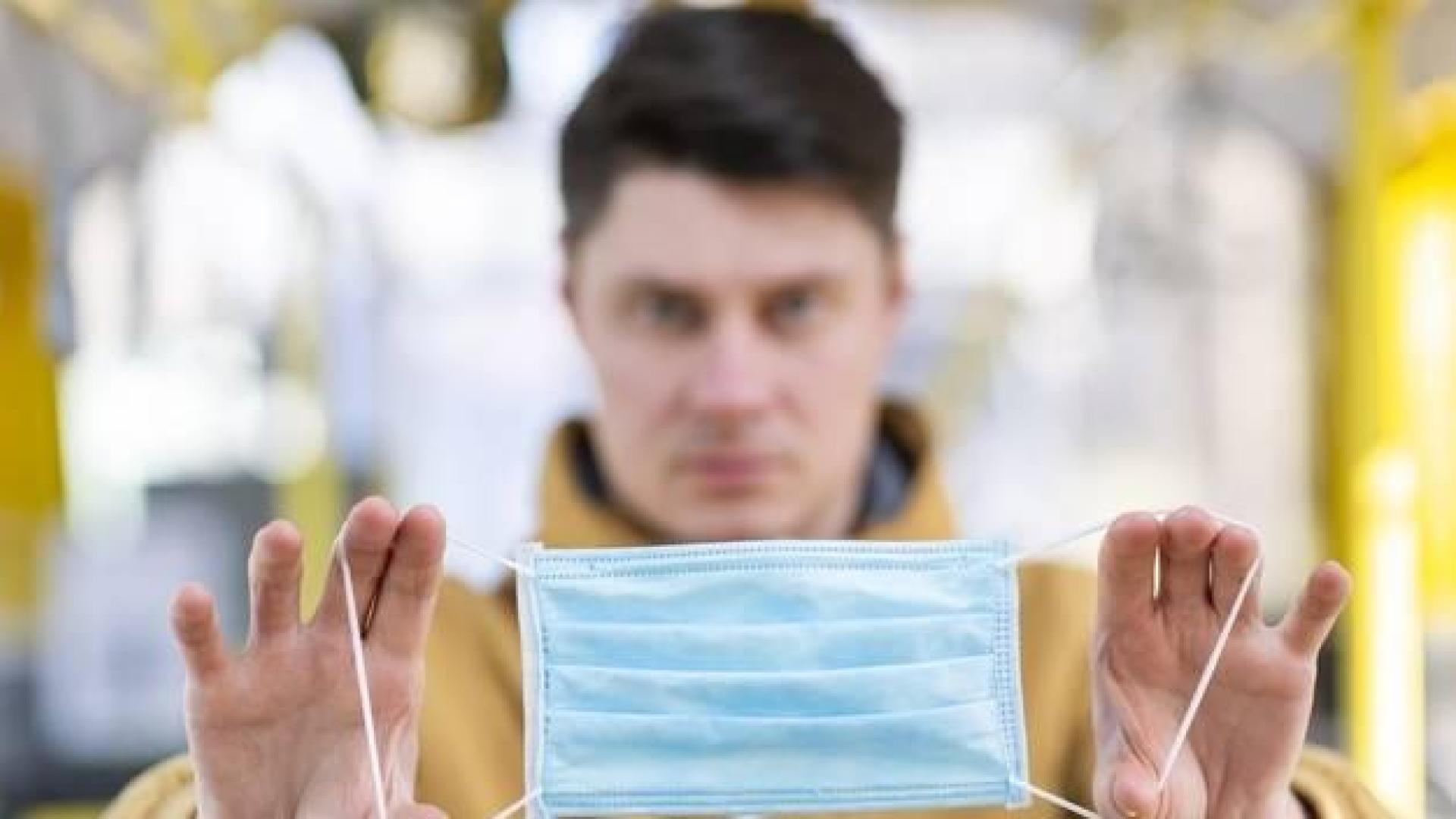 Un hombre sostiene una mascarilla quirúrgica entre sus manos