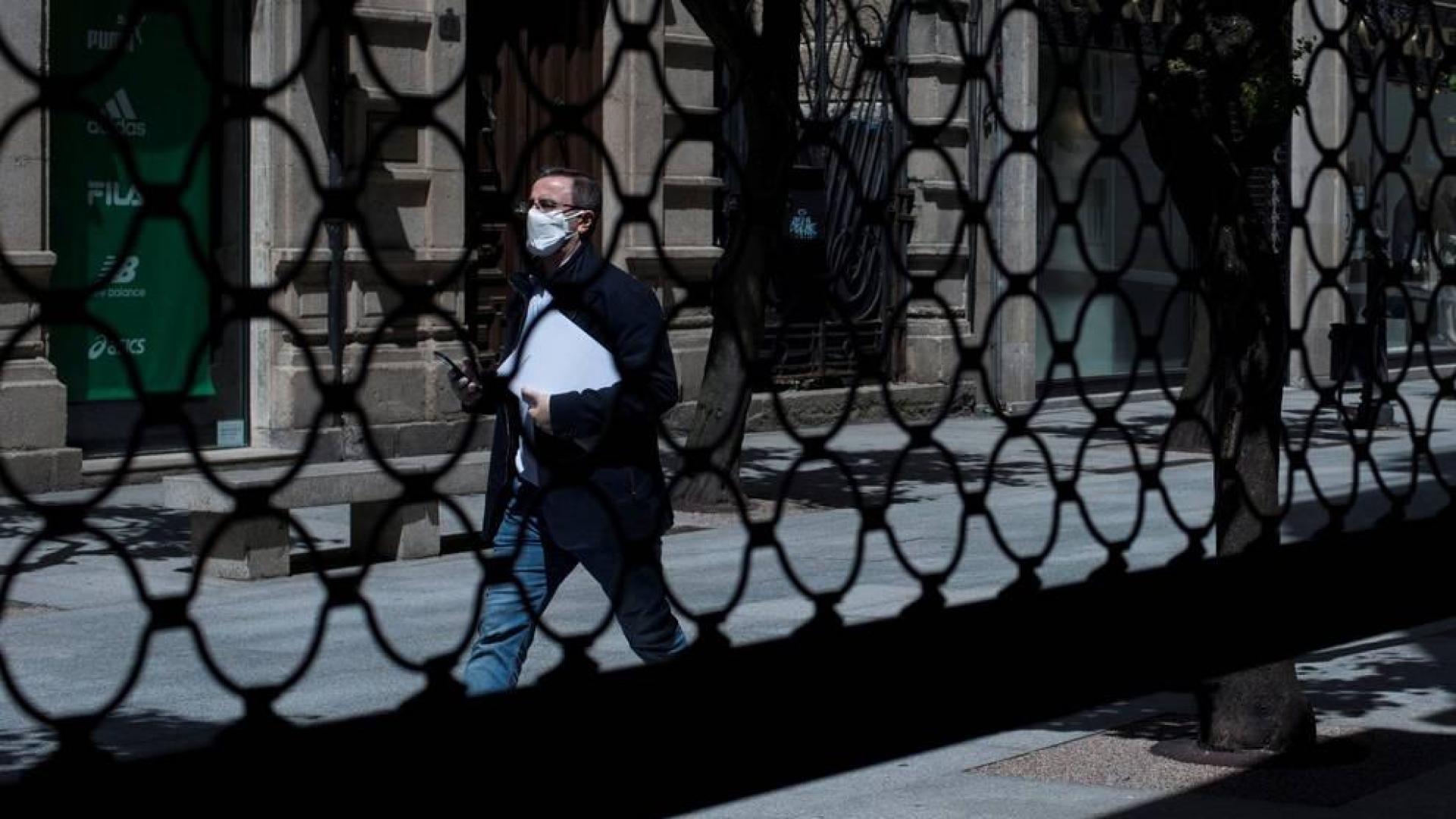 Un hombre camina por una calle por delante de la persiana semibajada de un comercio en los meses más duros de la pandemia.