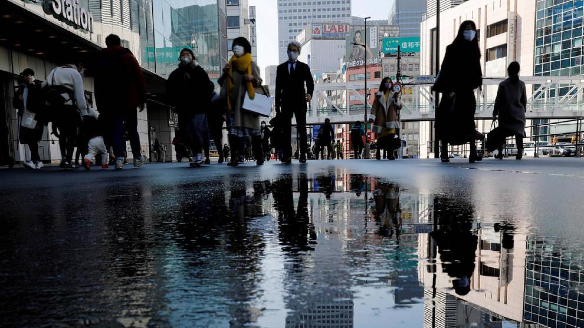 Ciudadanos japoneses con mascarilla pasean por una calle de Tokyo antes del terremoto