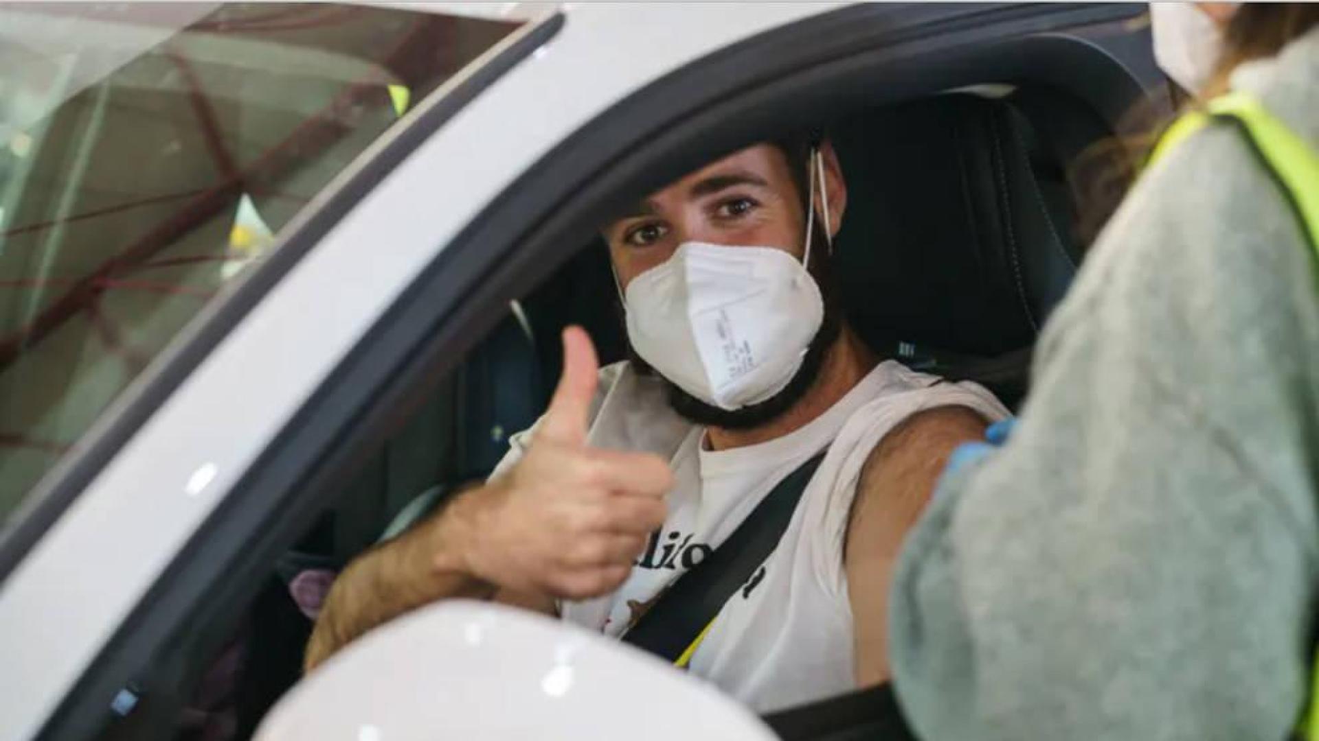 Un joven saluda después de ser vacunado en el interior de su coche.