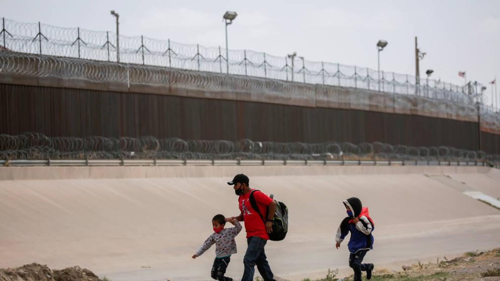 Un padre con dos niños intentan cruzar la frontera entre México y Estados Unidos atravesando el río Bravo