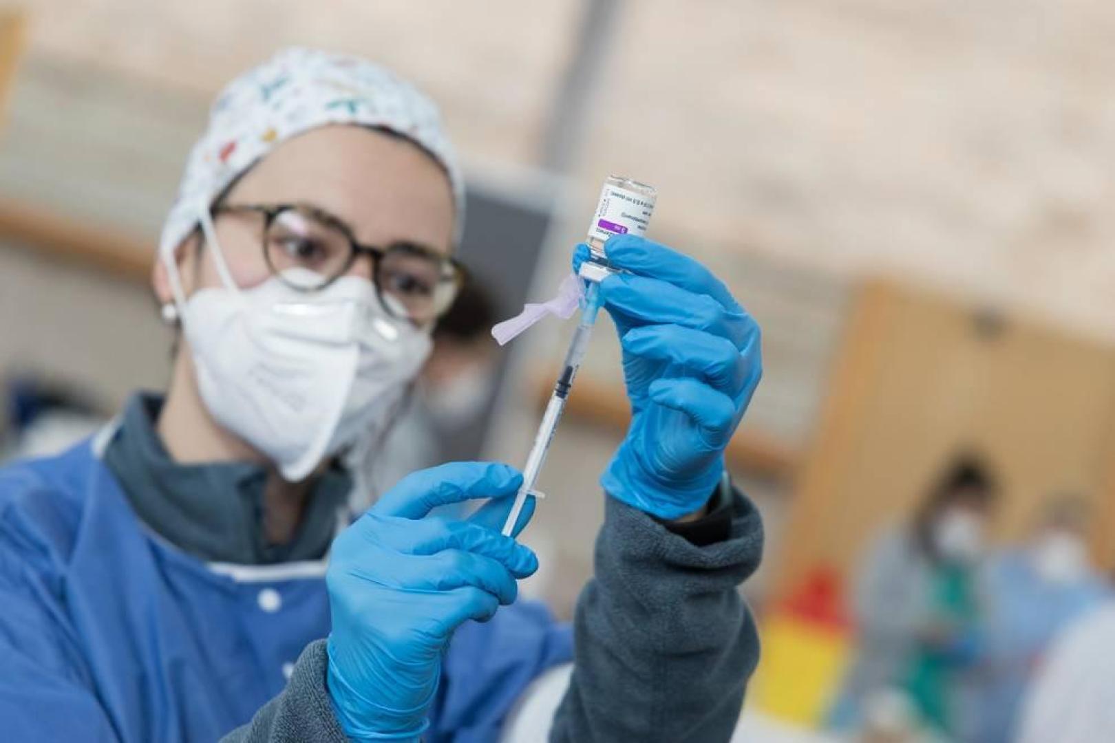 Una sanitaria carga una jeringa.