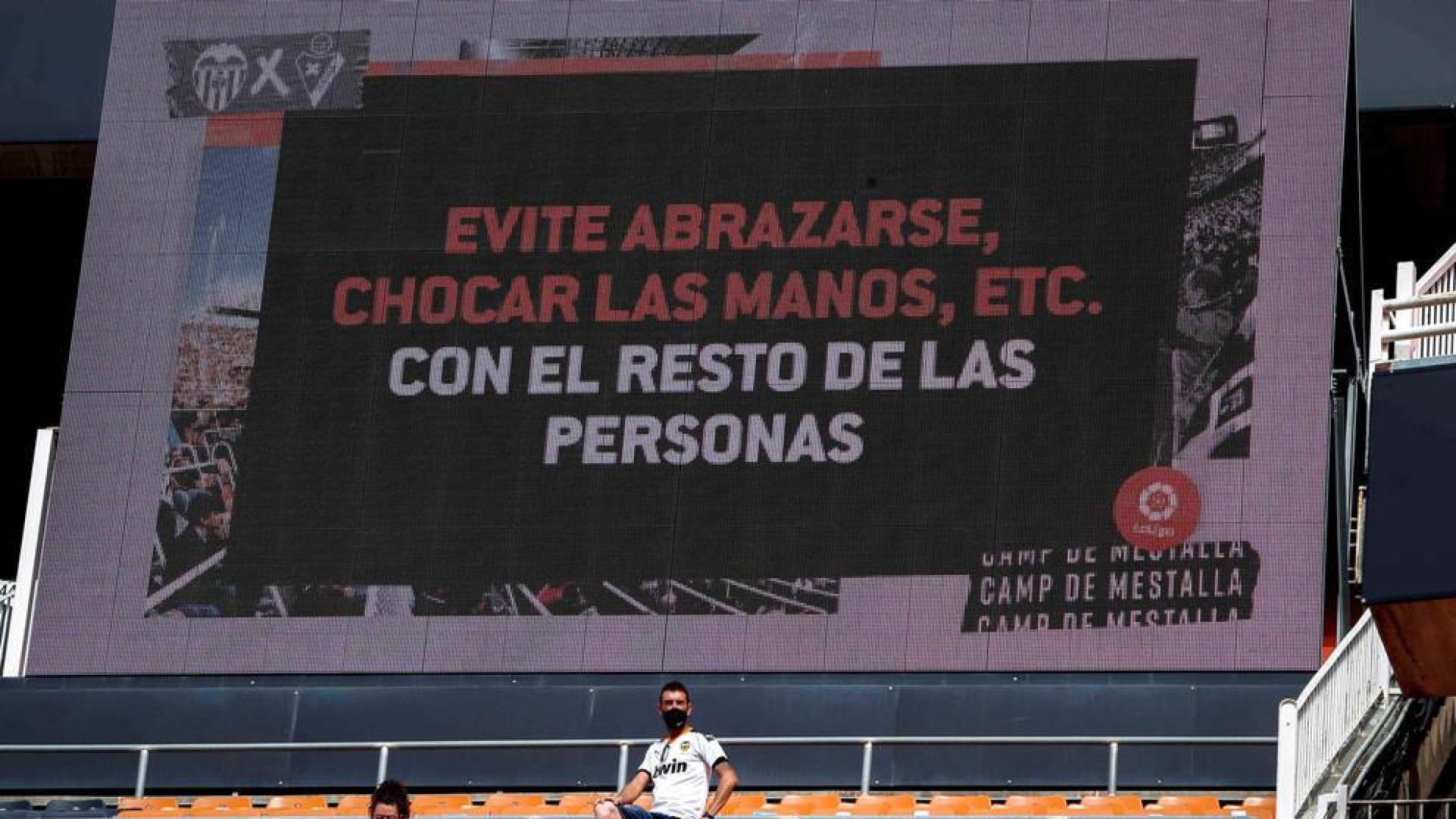 Dos aficionados en Mestalla con un mensaje a sus espaldas.