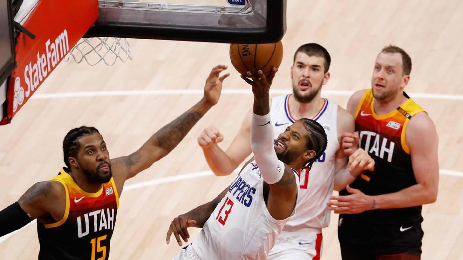 El escolta de Los Angeles Clippers Paul George conduce el balón al aro contra Derrick Favors de Utah Jazz.